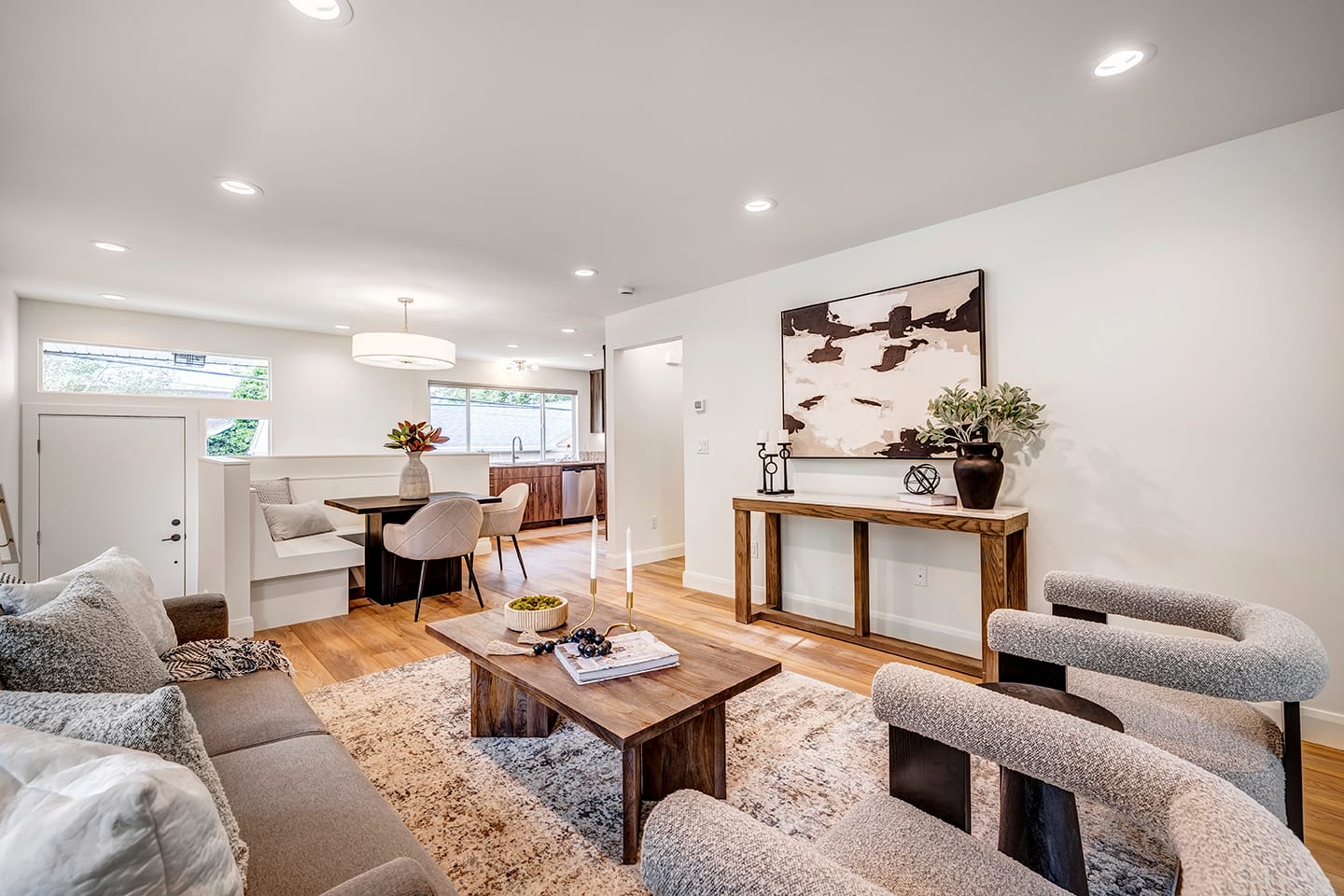 Living room with chic furniture looking toward the entry, dining nook, hallway, and kitchen.