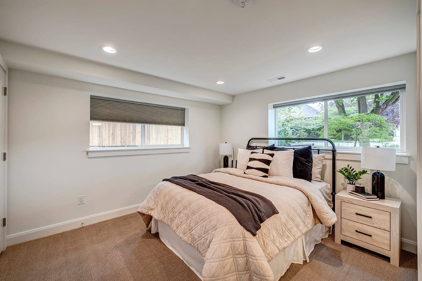 Bed with nightstands on either side and two large windows.