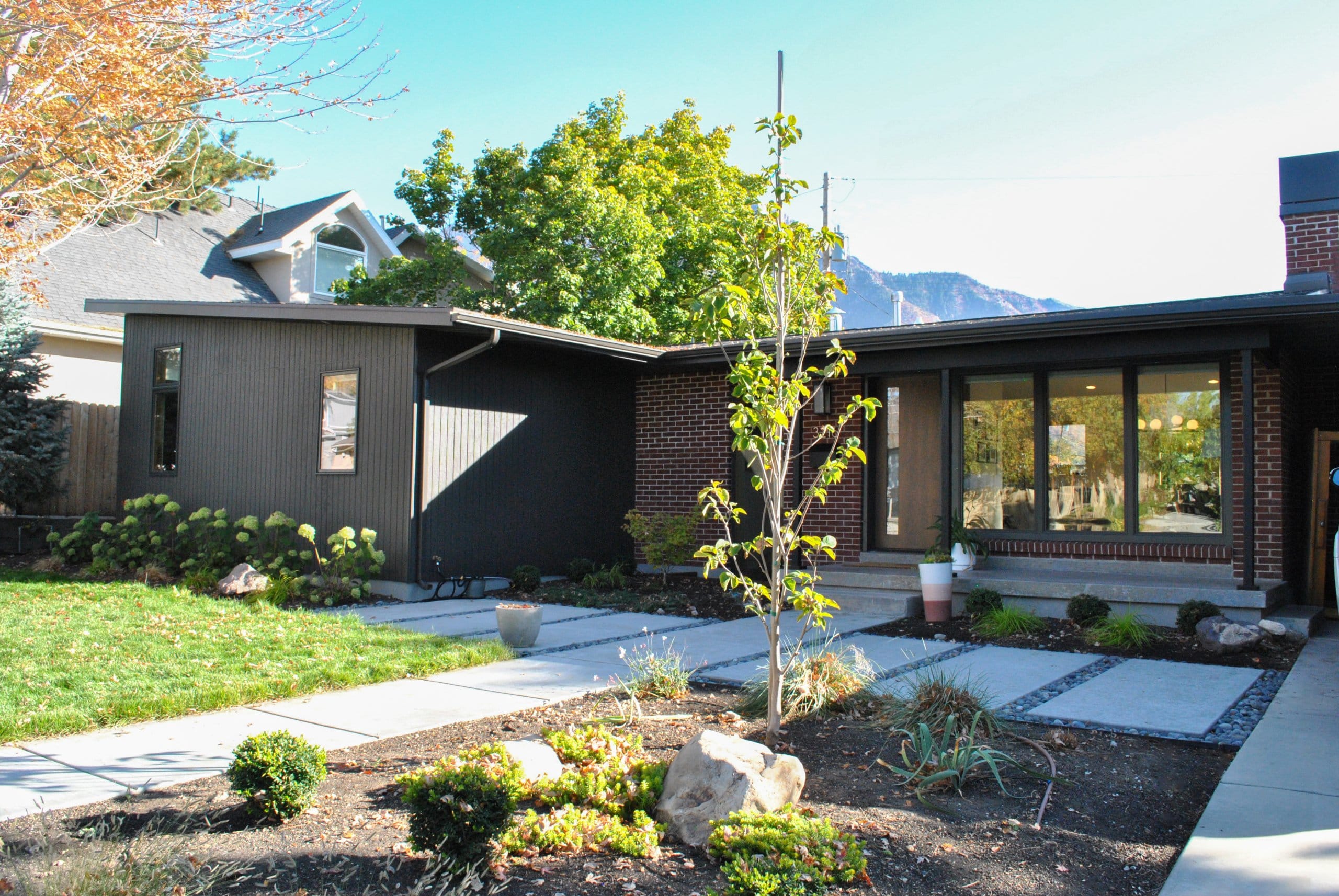 Mid-century modern house exterior with a covered front porch, new landscaping, and large windows.