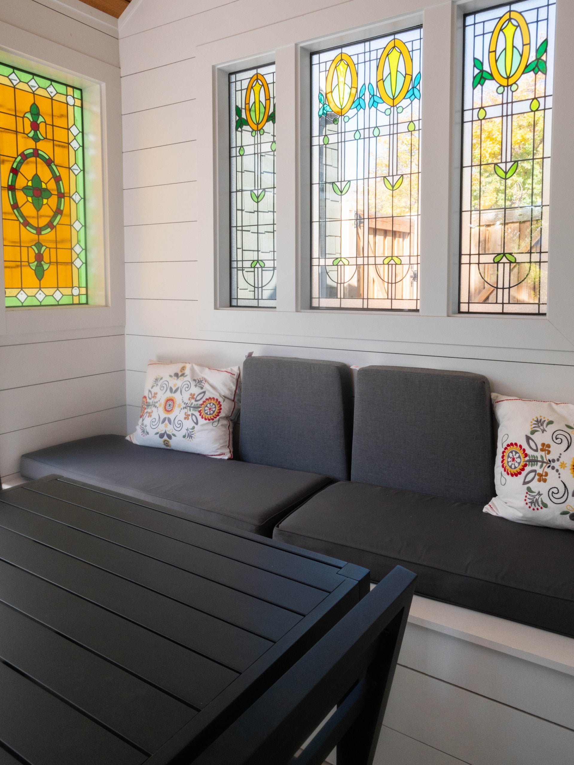 Covered patio with a table and chairs, built-in bench, and stained glass windows.
