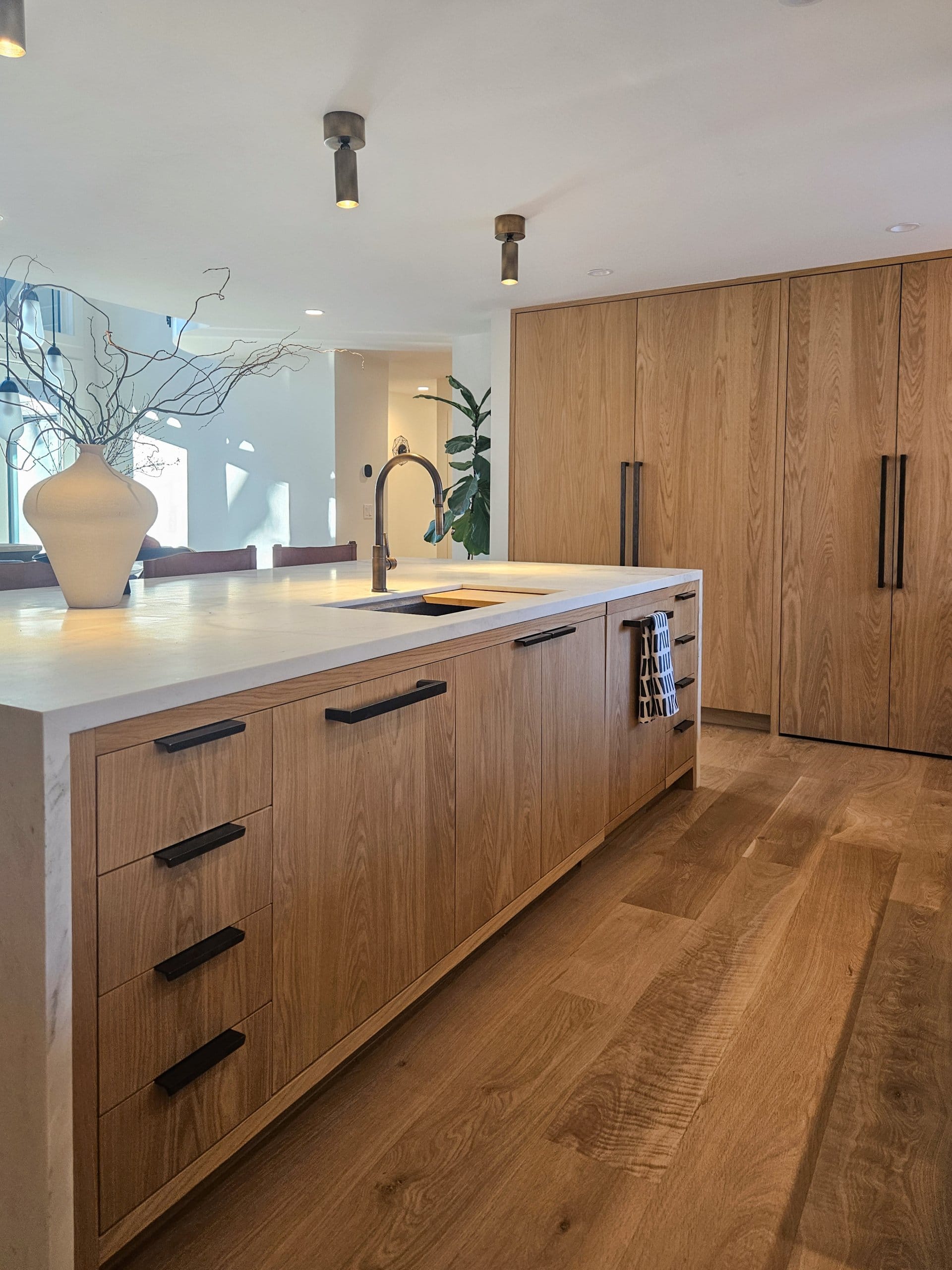 Kitchen island with sink, built-in fridge and freezer combination, and a hidden pantry.