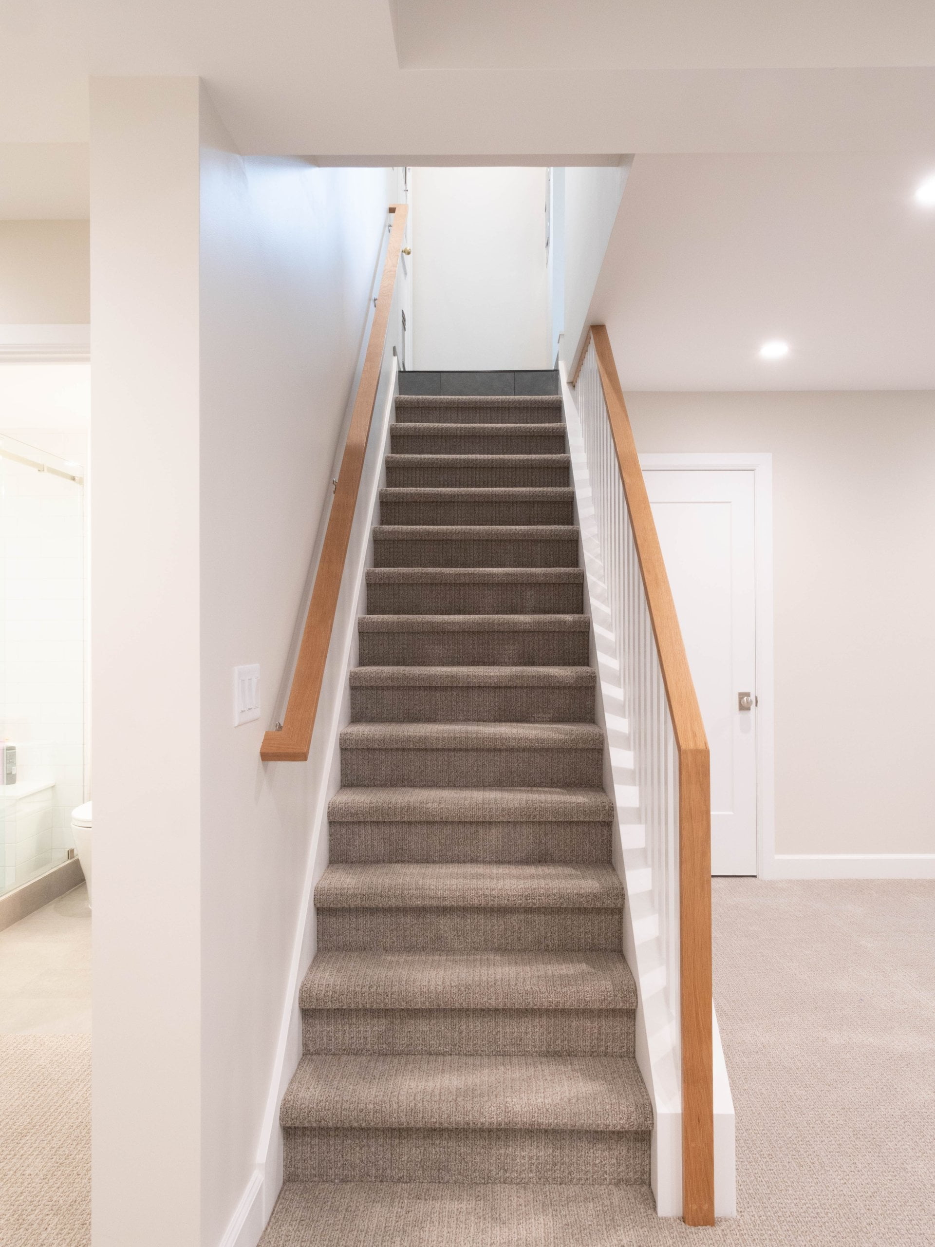 Staircase after the remodel with carpet and a wood railing.