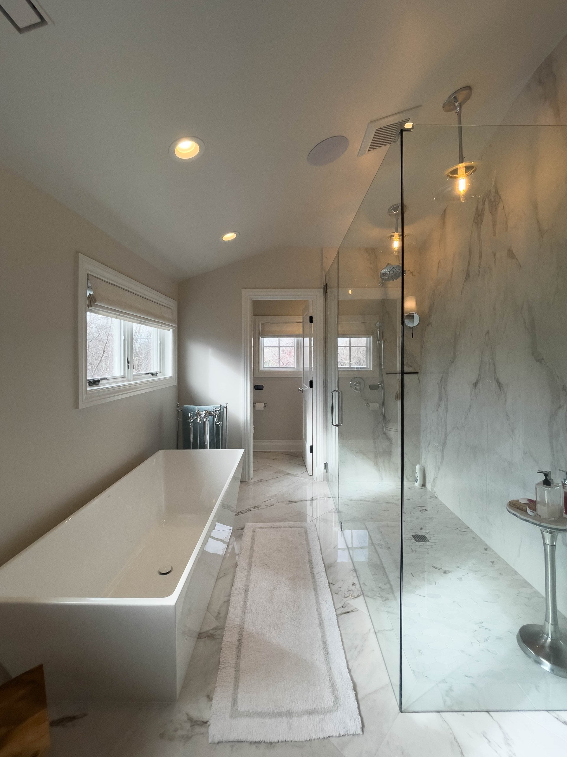 Primary bathroom looking toward the water closet. On the right, is a large shower. On the left is a large bath tub.