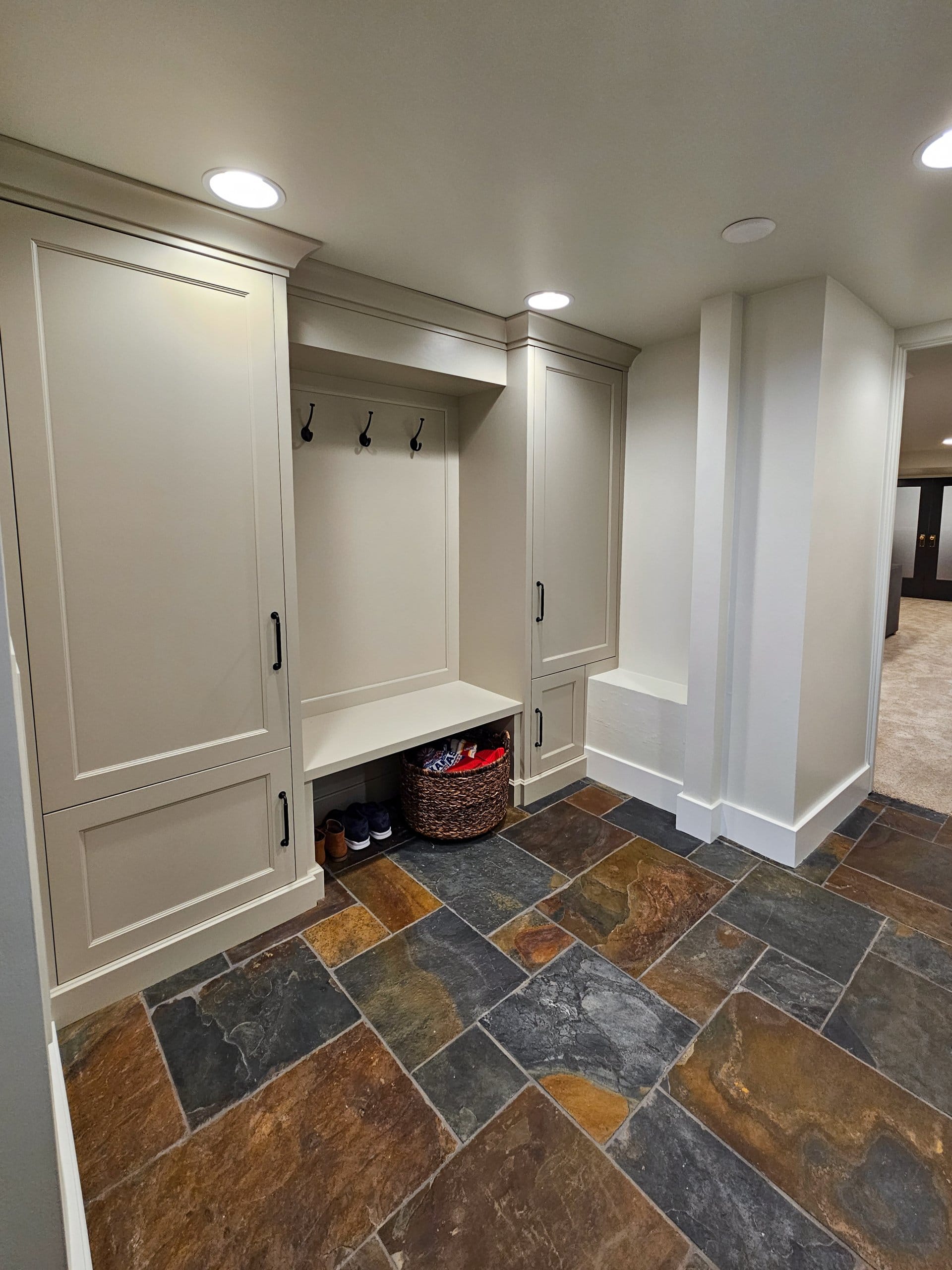 Basement mudroom with built-in cabinets on either side of a bench.