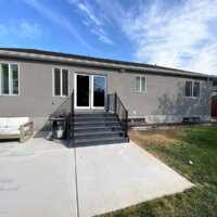 Thumbnail of http://Back%20of%20the%20house%20with%20a%20lawn,%20patio,%20and%20stairs%20down%20from%20the%20door.