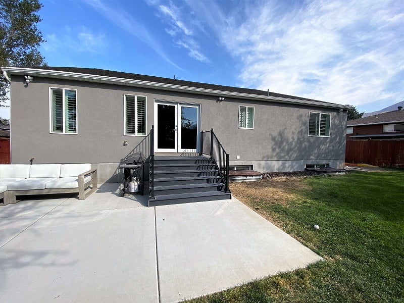 Back of the house with a lawn, patio, and stairs down from the door.