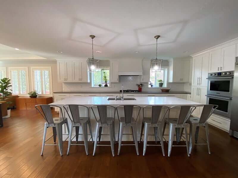Large and open concept kitchen that includes double ovens, an island with seating for seven and a sink, and lots of storage.