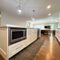 Thumbnail of http://Large%20kitchen%20island%20with%20microwave,%20sink,%20and%20dishwasher.%20On%20the%20floor%20in%20front%20are%20two%20area%20rugs.