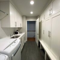 Thumbnail of http://Laundry%20and%20mudroom%20combination%20with%20built-in%20cabinets,%20a%20sink,%20side-by-side%20washer%20and%20dryer,%20and%20a%20door%20that%20leads%20to%20the%20hallway.