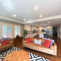 Thumbnail of http://Living%20room%20with%20an%20open%20concept%20layout%20to%20the%20kitchen.%20The%20living%20room%20includes%20two%20couches,%20a%20rug,%20an%20ottoman,%20plants,%20and%20a%20credenza.