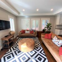 Thumbnail of http://Living%20room%20with%20two%20couches,%20a%20rug,%20an%20ottoman,%20plants,%20a%20credenza,%20and%20a%20TV%20mounted%20on%20the%20wall%20with%20a%20side%20table%20below.