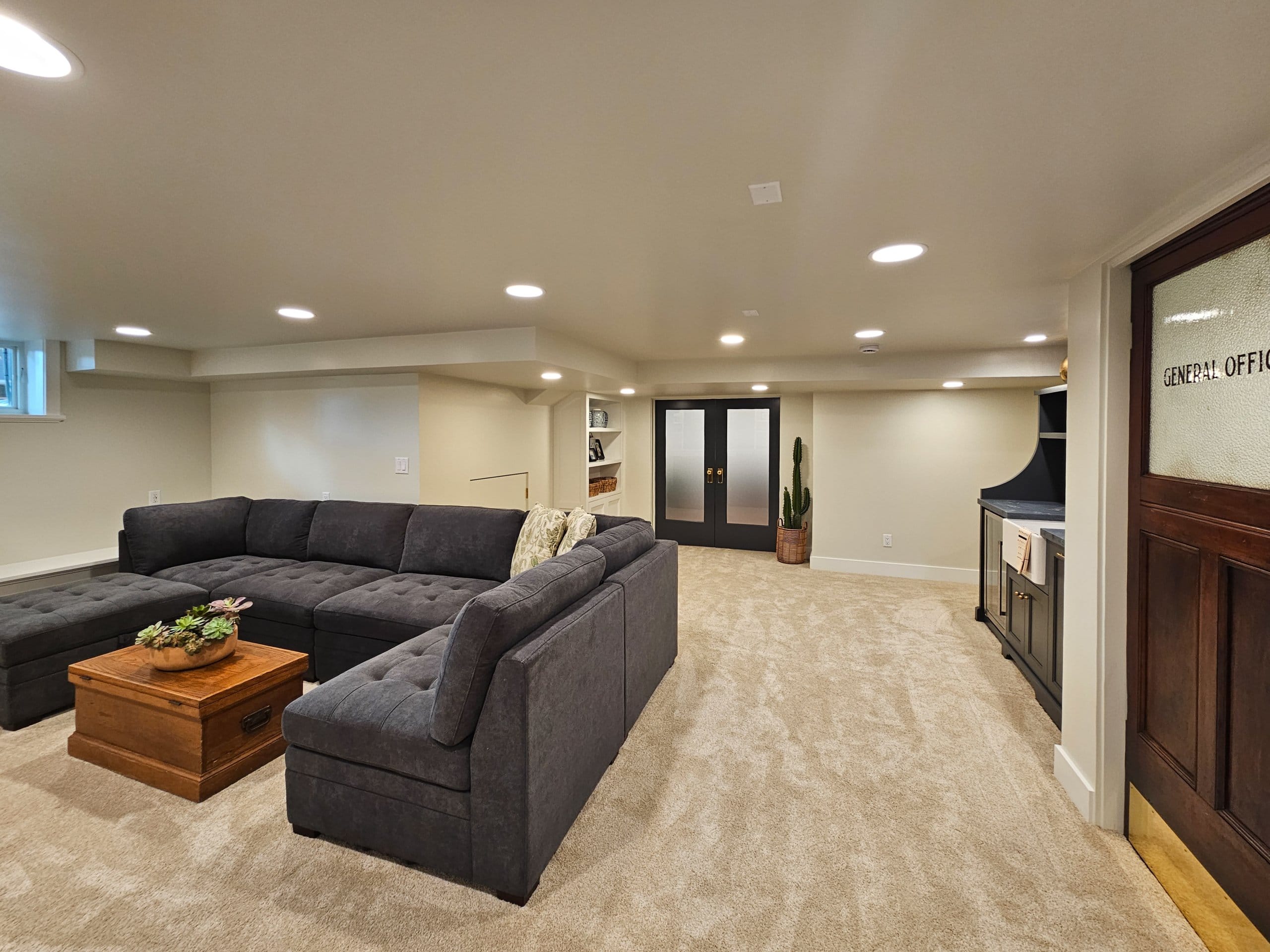 Large basement family room with a couch and coffee table, french doors to the craft room, and a built-in wet bar.