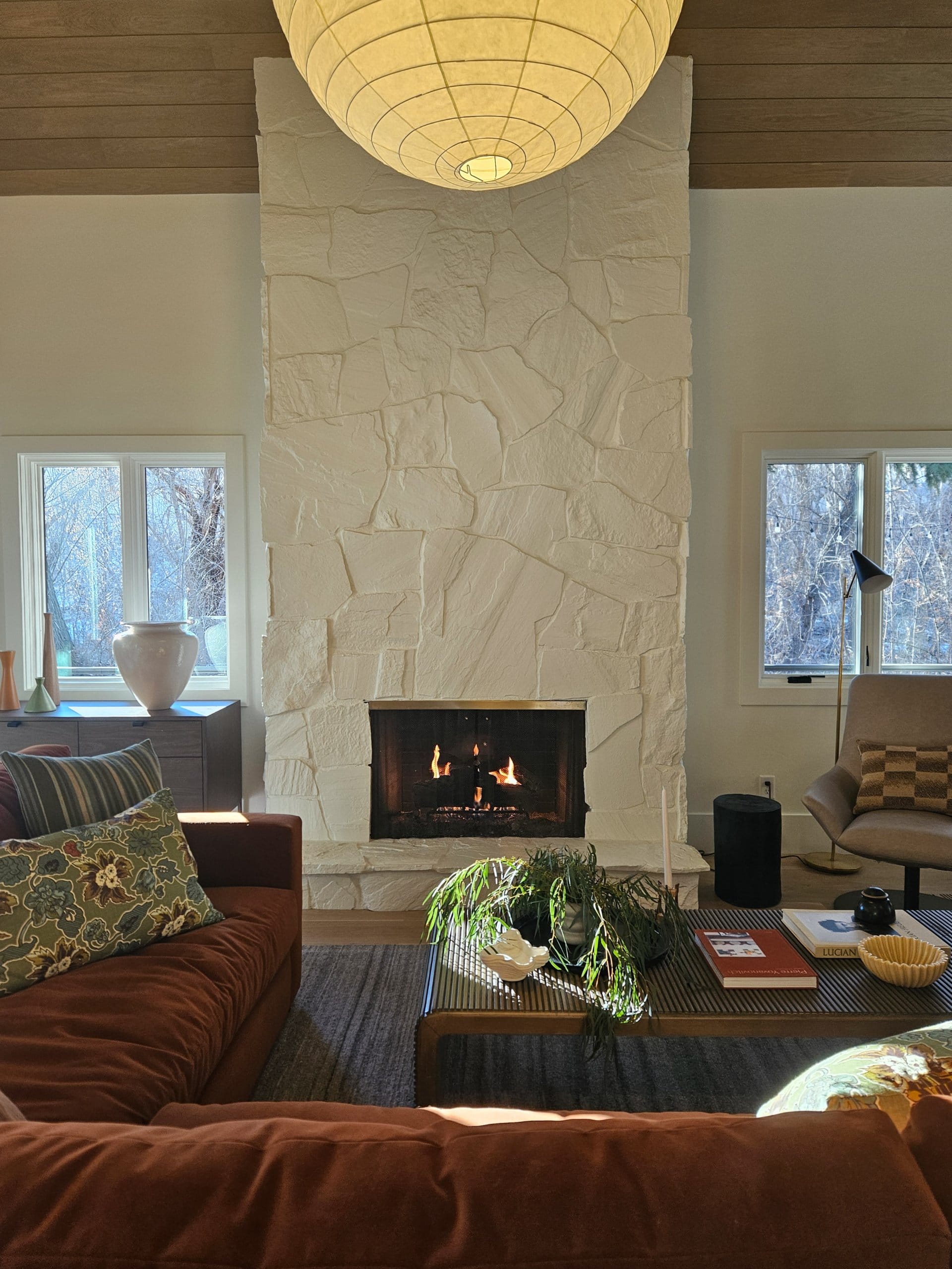 Living room stone fireplace with windows on either side.