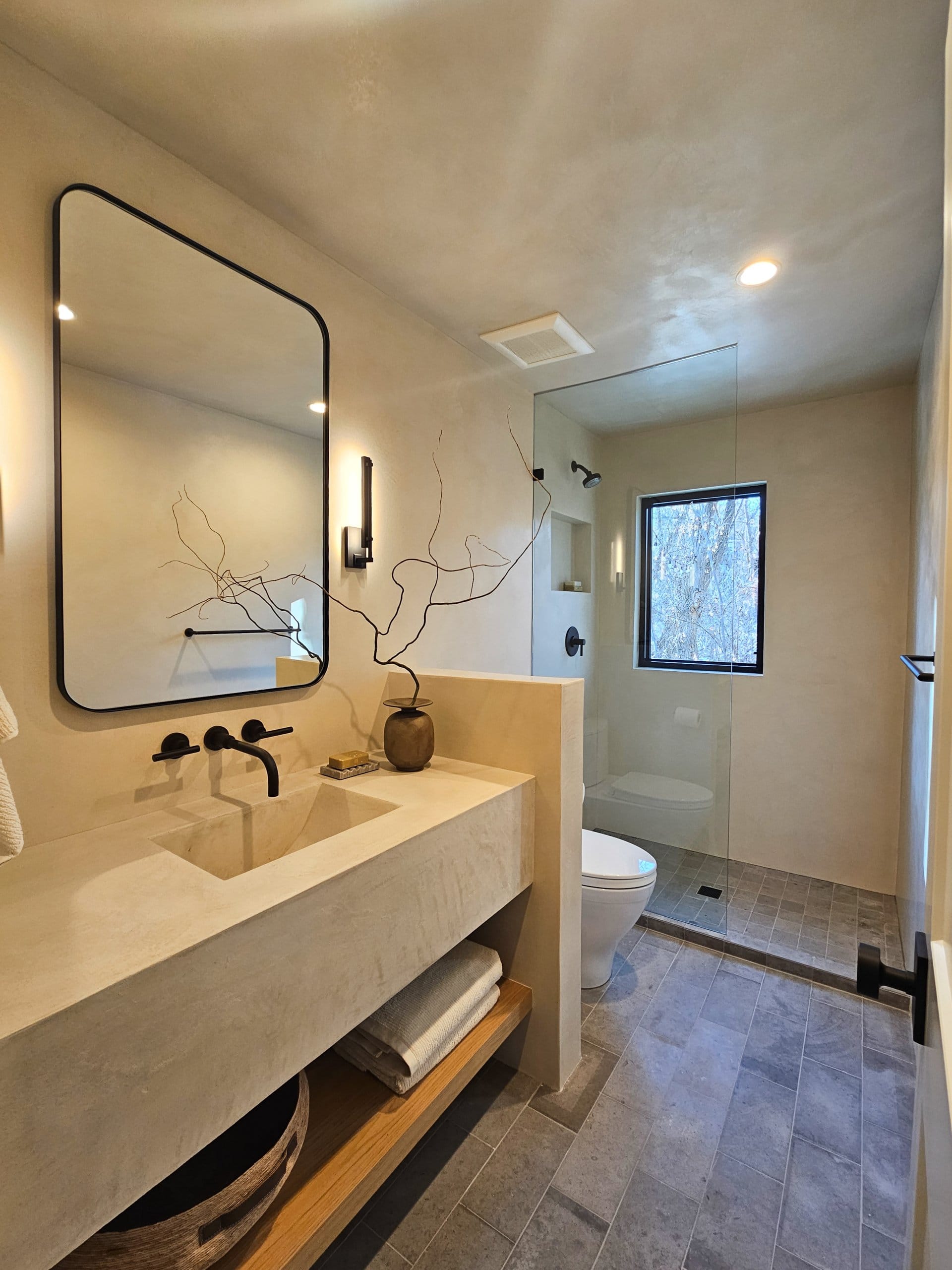 Bathroom with open storage under the sink, a toilet, and a shower.