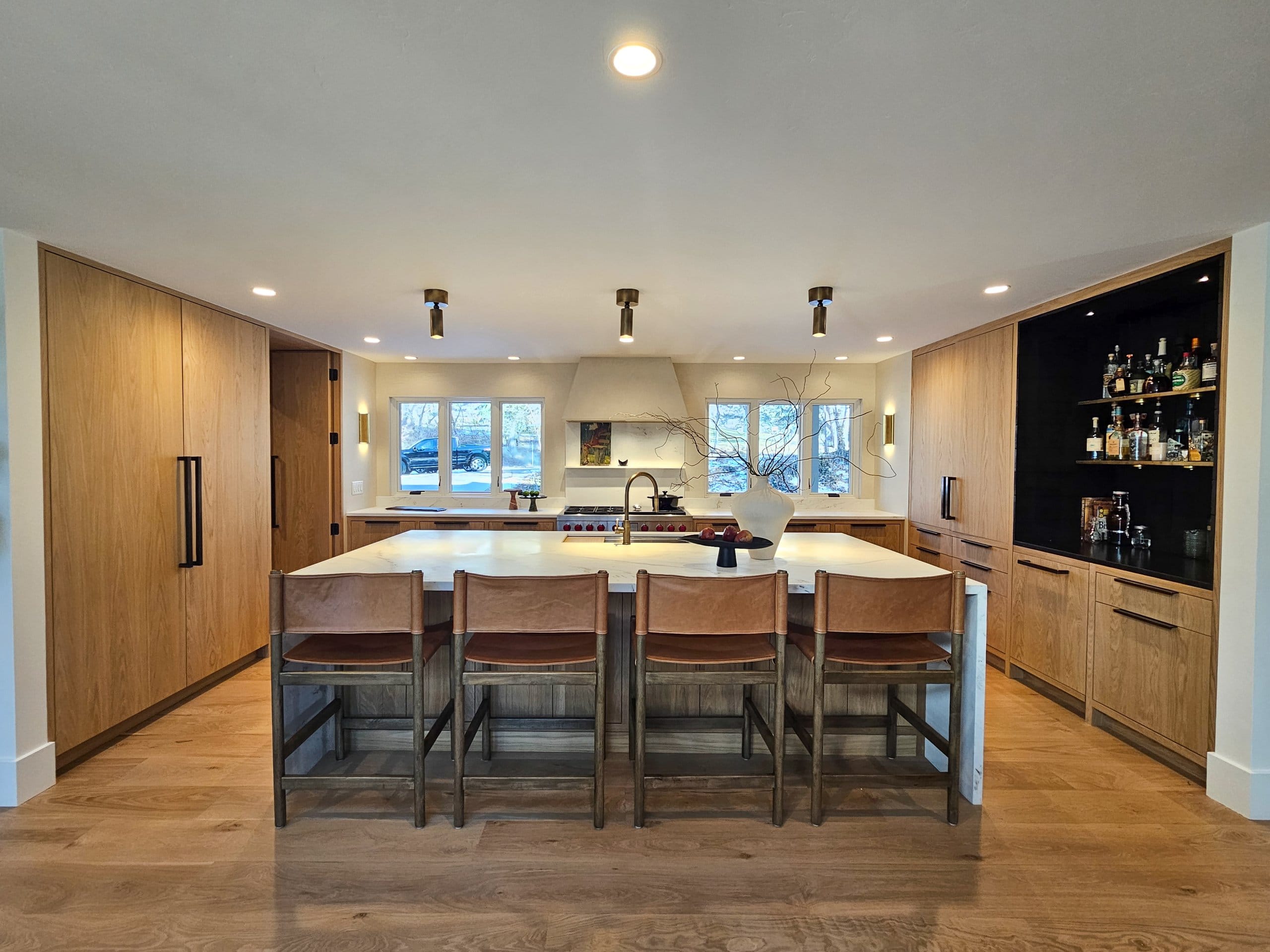 Large kitchen with an island, range centered between the windows, bar, and hidden pantry.