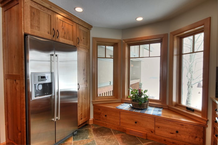 After_Interior_Great Room Designs_1980's Home Update_stone in the kitchen_Tile and wood flooring together_pendulum lights_Kitchen island bar_Bar stools_Window Seats | Renovation Design Group