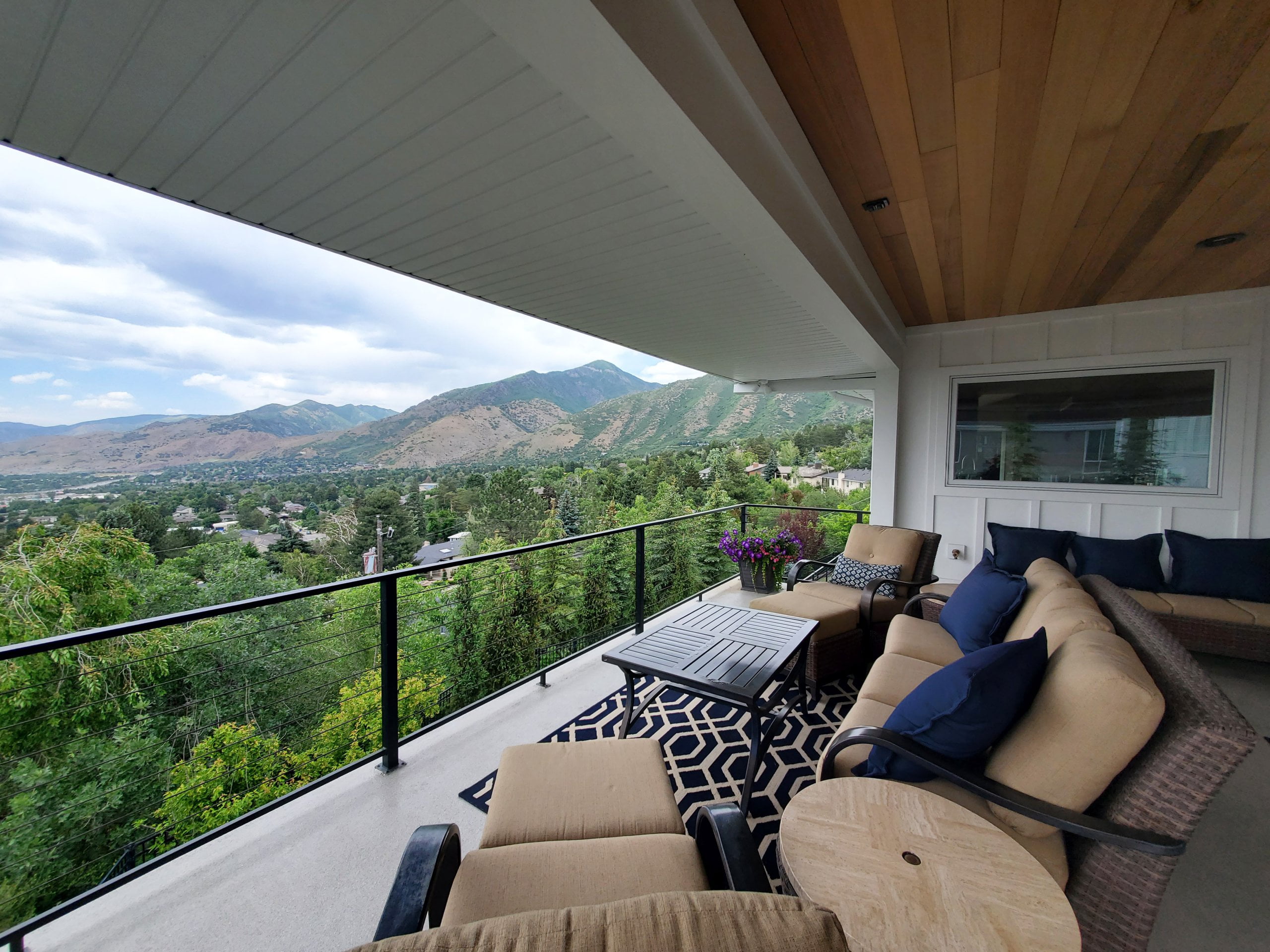 Covered deck with outdoor furniture and a view of the mountains.