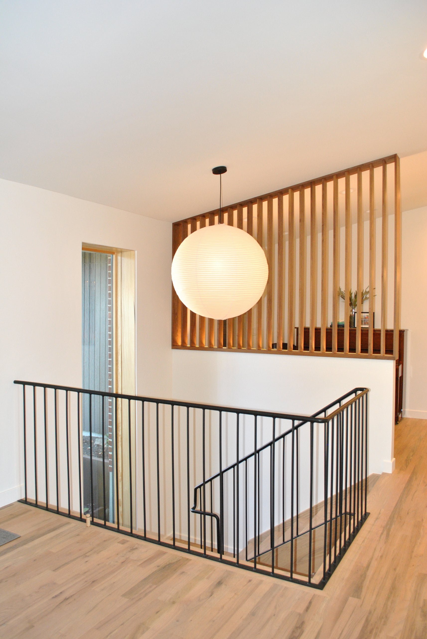 Mid-century modern staircase with a metal railing on one side and a partial wall and wood divider on the other side.