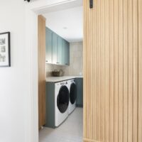 Thumbnail of http://Wood%20barn%20door%20part%20way%20open%20with%20view%20into%20the%20large%20laundry%20room.%20The%20laundry%20room%20features%20cabinetry%20painted%20in%20a%20fun%20color,%20a%20folding%20counter%20above%20the%20side-by-side%20washer%20and%20dryer,%20and%20a%20spacious%20layout.