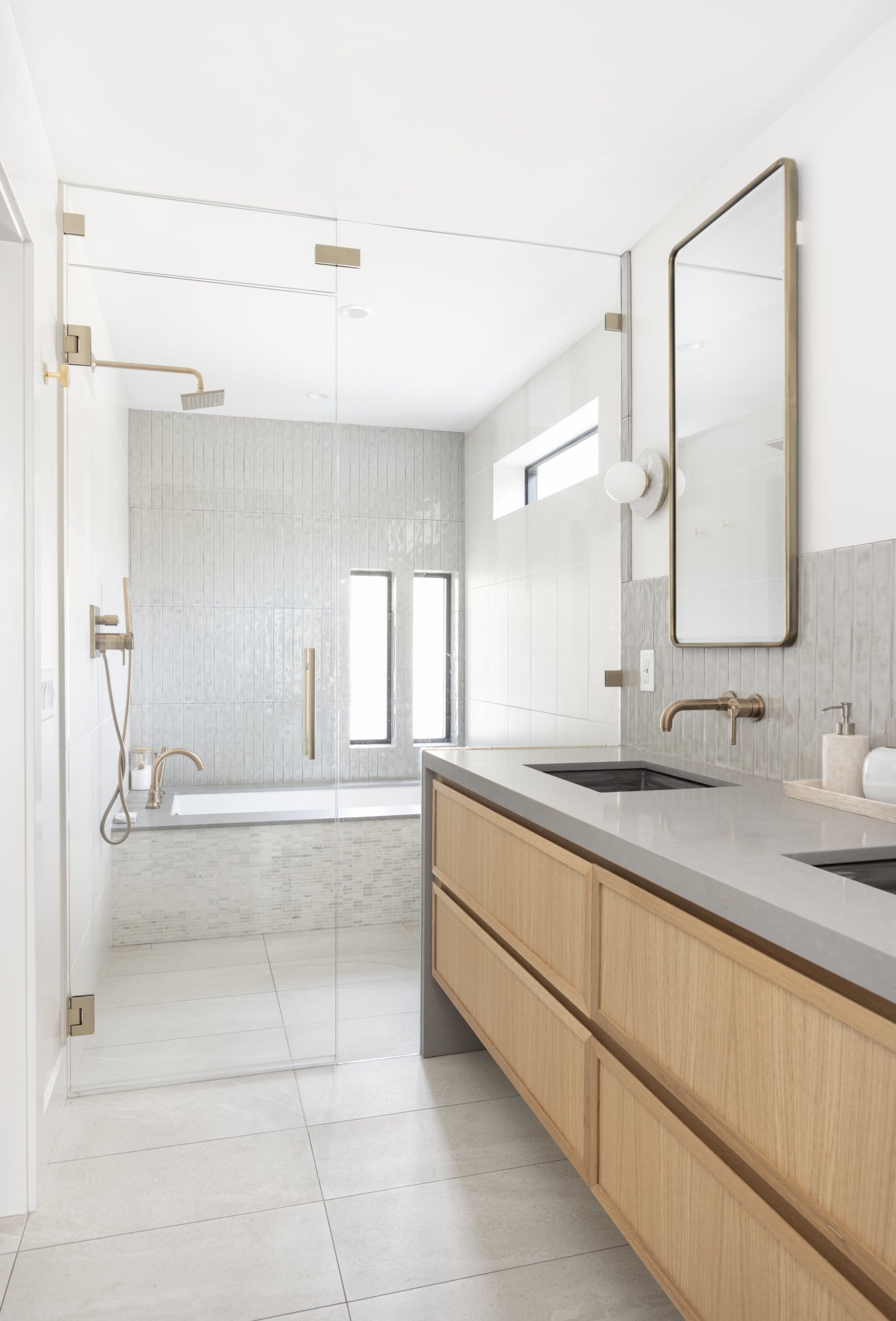 Modern primary bathroom looking past the double sinks to the wet room with the shower and large tub.