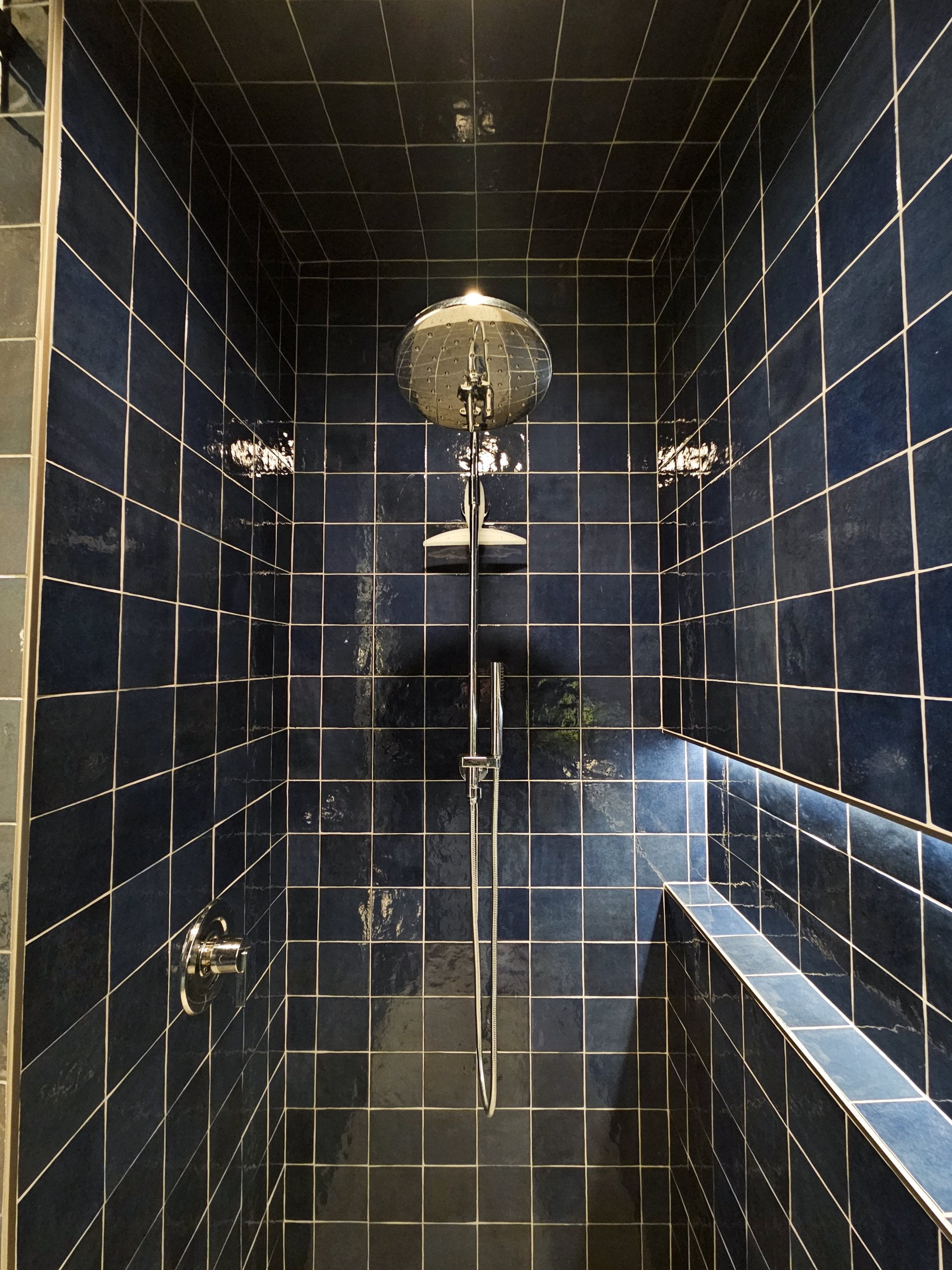 Shower with blue tile and niche to the side.