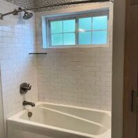 Thumbnail of http://Bath%20tub%20and%20shower%20combination%20with%20a%20frosted%20window,%20shelf,%20and%20unique%20tile%20design.