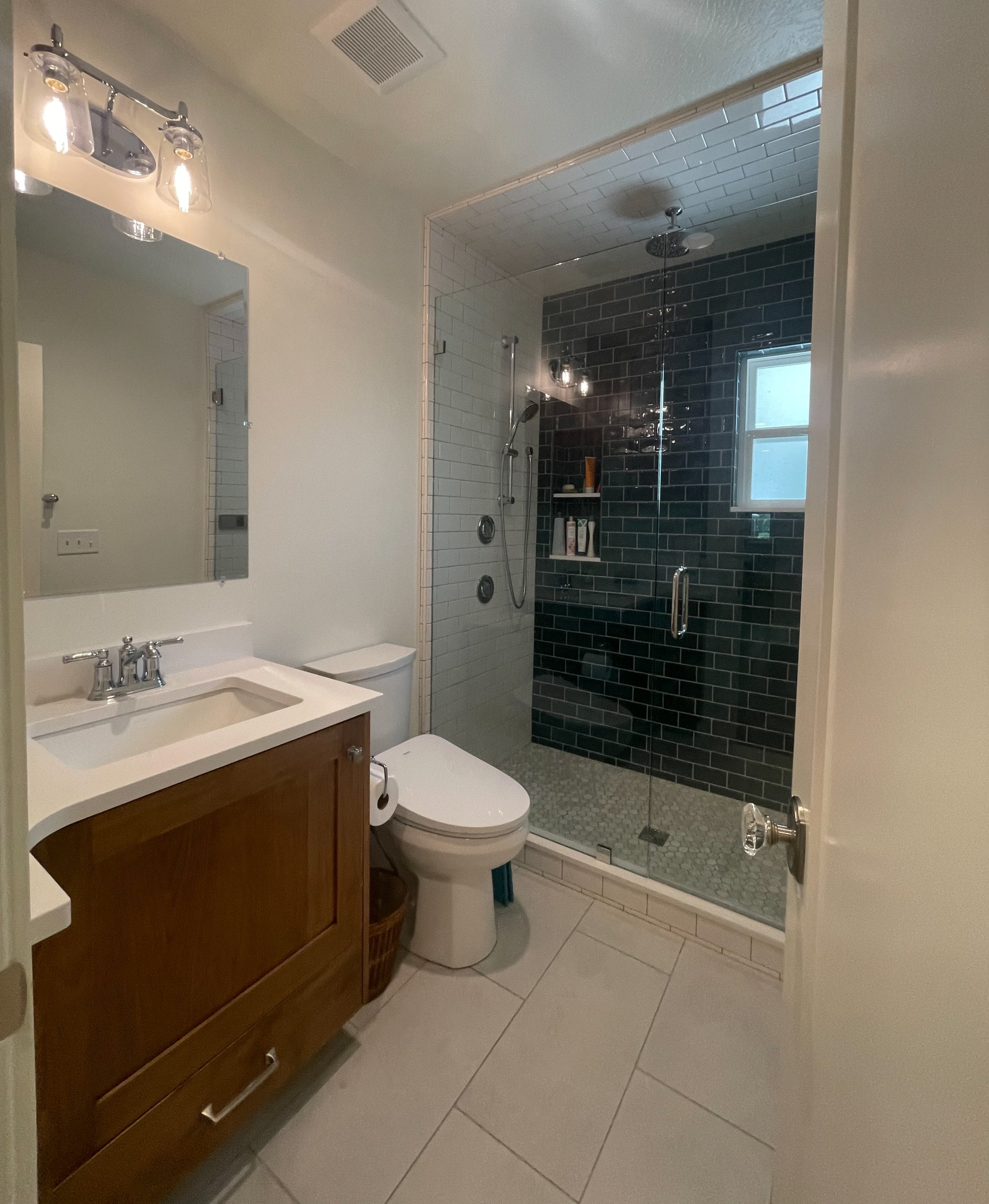 Renovated bathroom featuring a shower with blue and white tile.