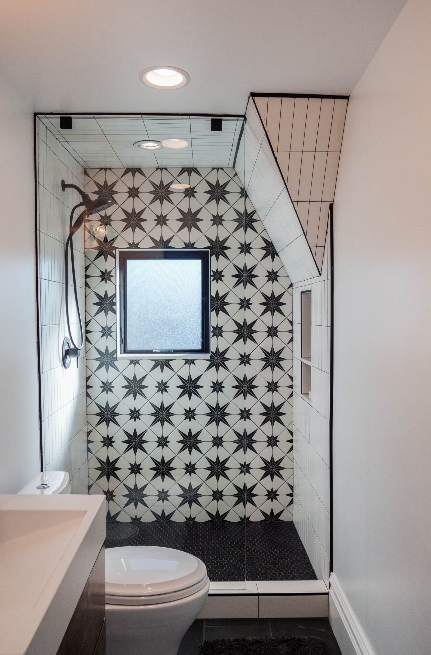 Shower with partially sloped wall, window, and niche.