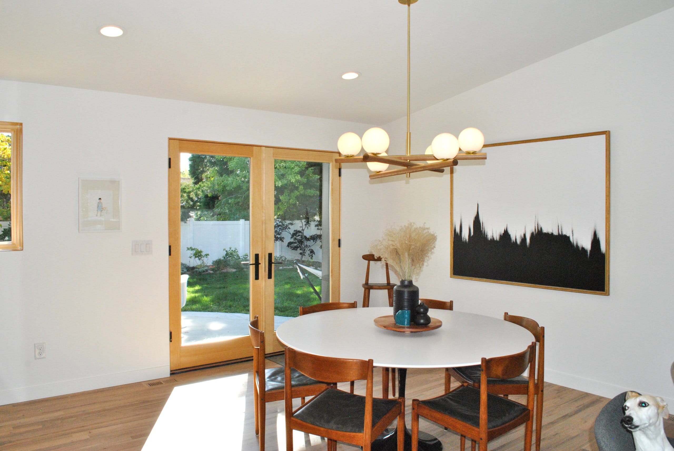 Dining room with a round table in the center that seats six and french doors behind.