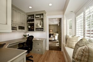 Home office with wrap around desk and a bay window with a cushioned window seat | Renovation Design Group