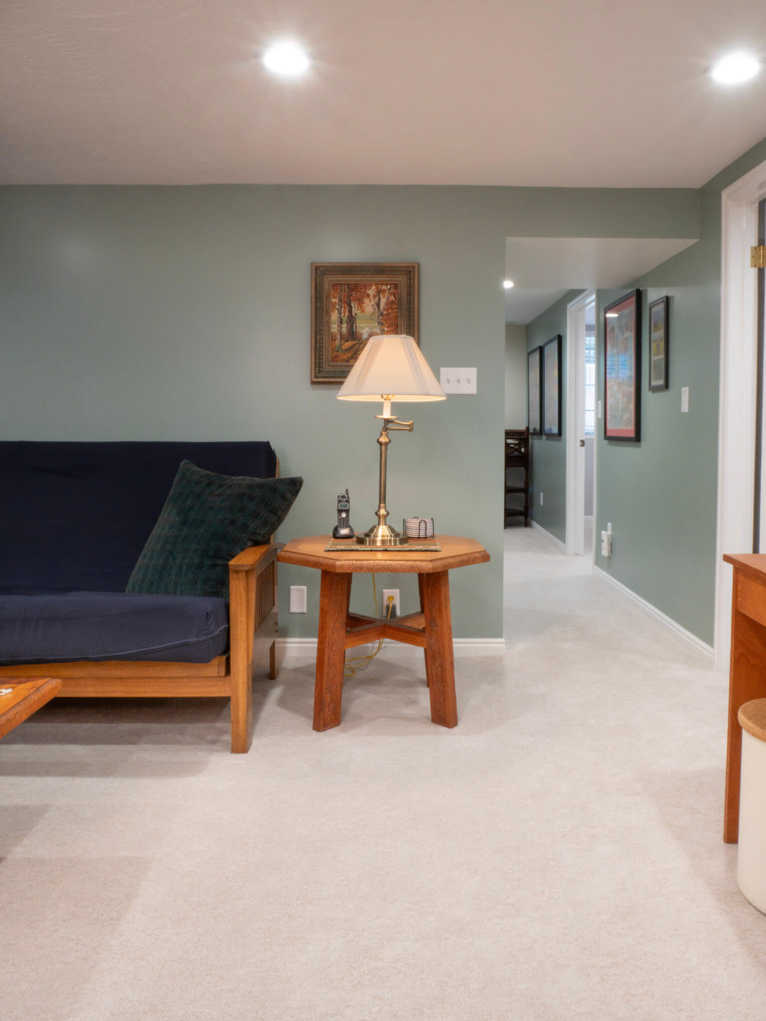 Basement family room looking at a couch, side table, and hallway.