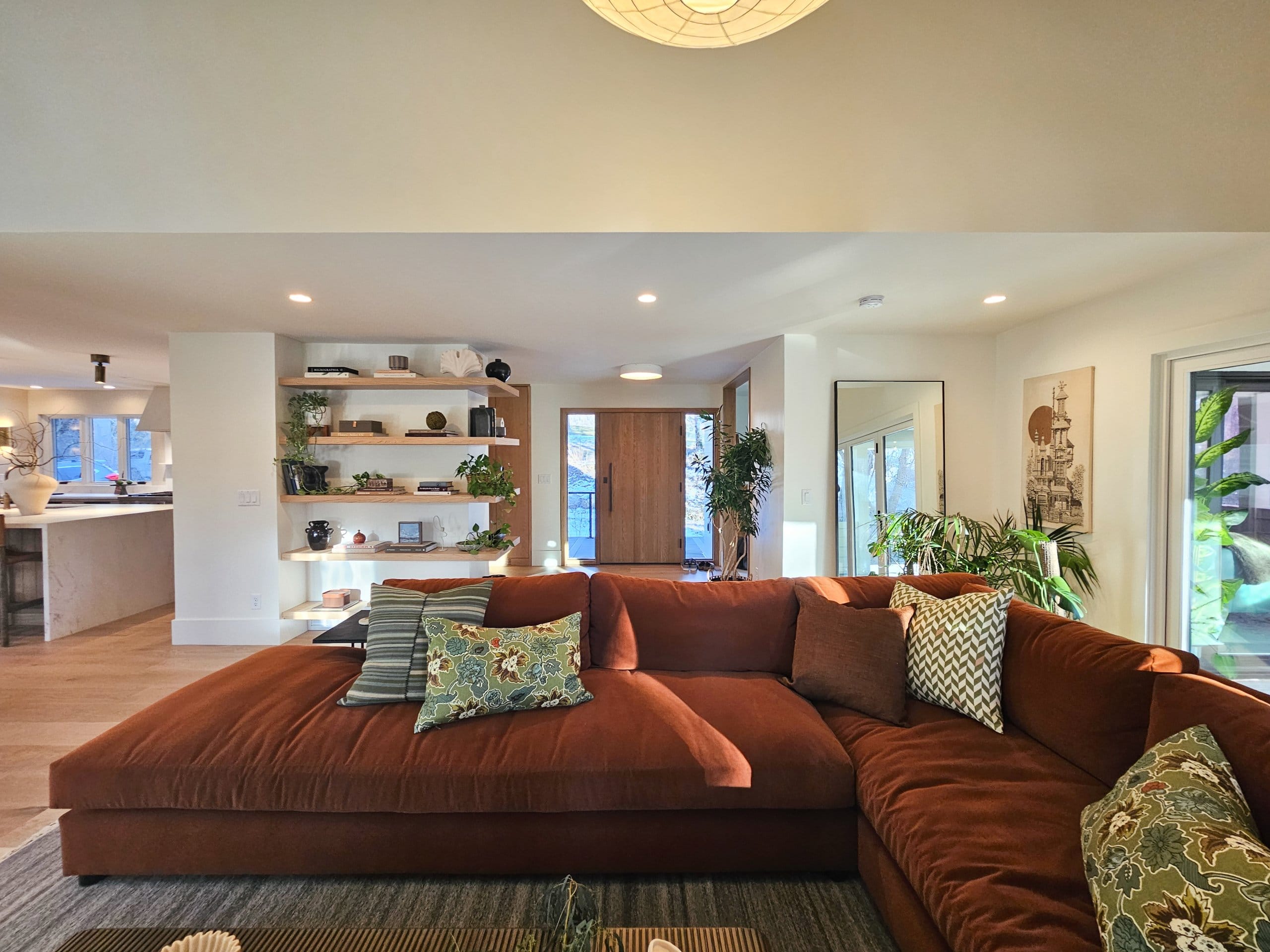 Living room with view of the large couch, entryway, and built-in shelves.