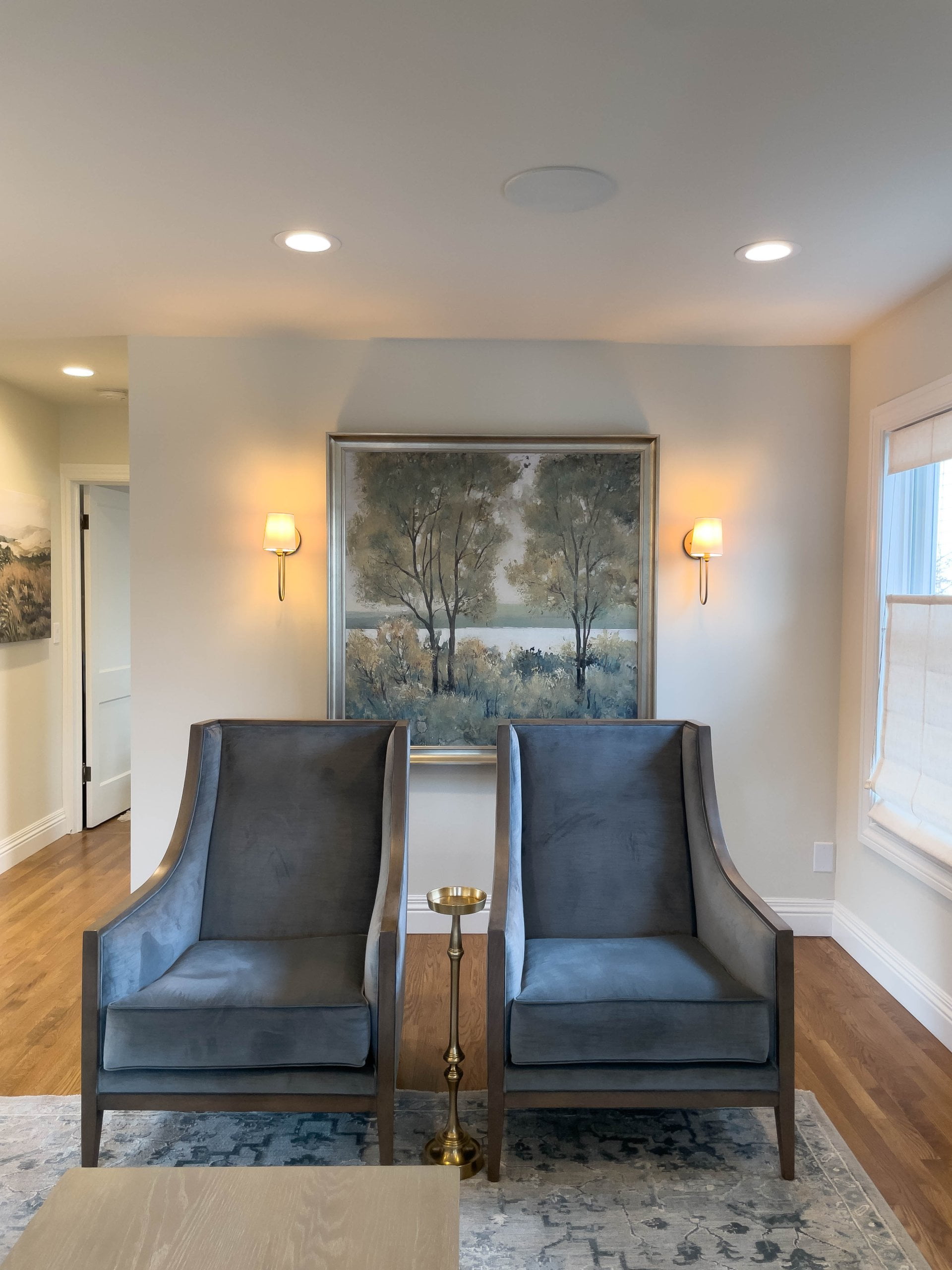 Two chairs and a small table under a painting in the family room.