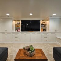 Thumbnail of http://Custom%20built-in%20shelves%20in%20the%20family%20room%20with%20storage,%20a%20large%20tv,%20and%20open%20shelves%20for%20books,%20decorations,%20and%20framed%20photos.