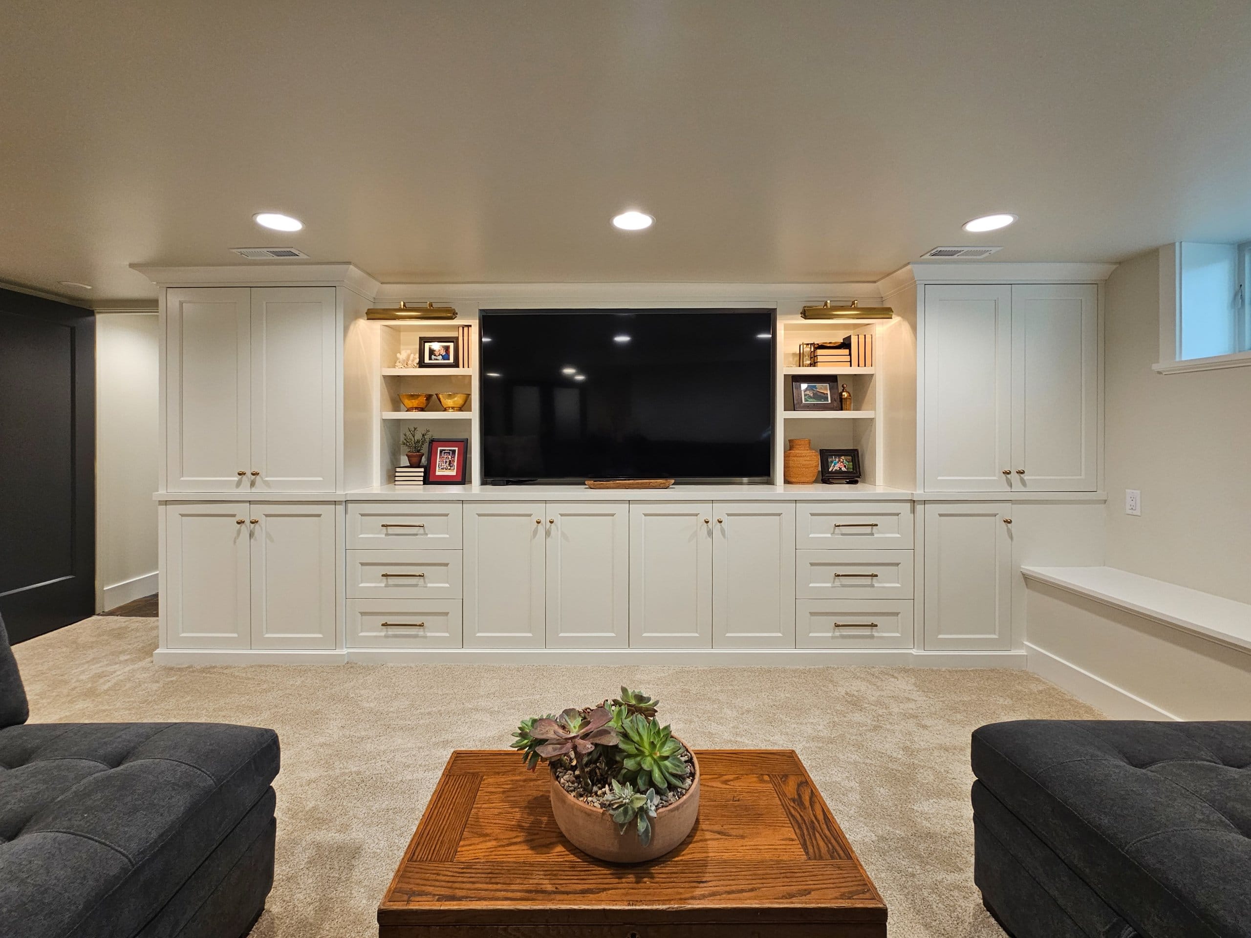 Custom built-in shelves in the family room with storage, a large tv, and open shelves for books, decorations, and framed photos.