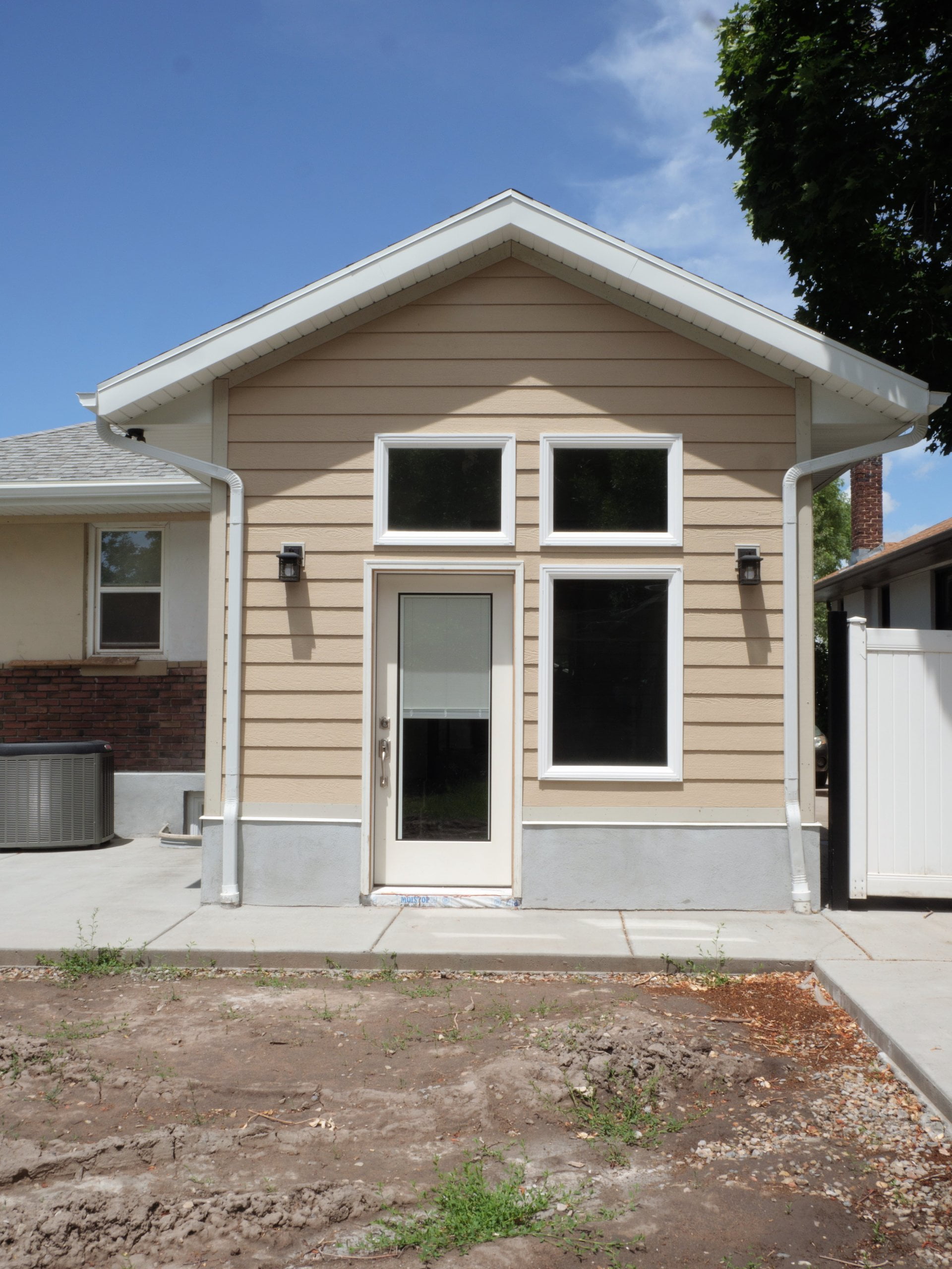 Small addition exterior view from the backyard with windows and a door.