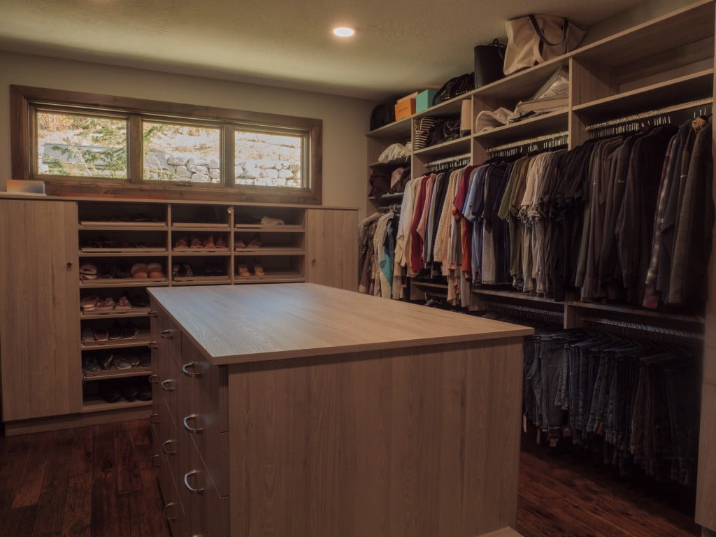 Large walk-in closet with an island in the center, shoe storage, and hanging space for shirts and pants.