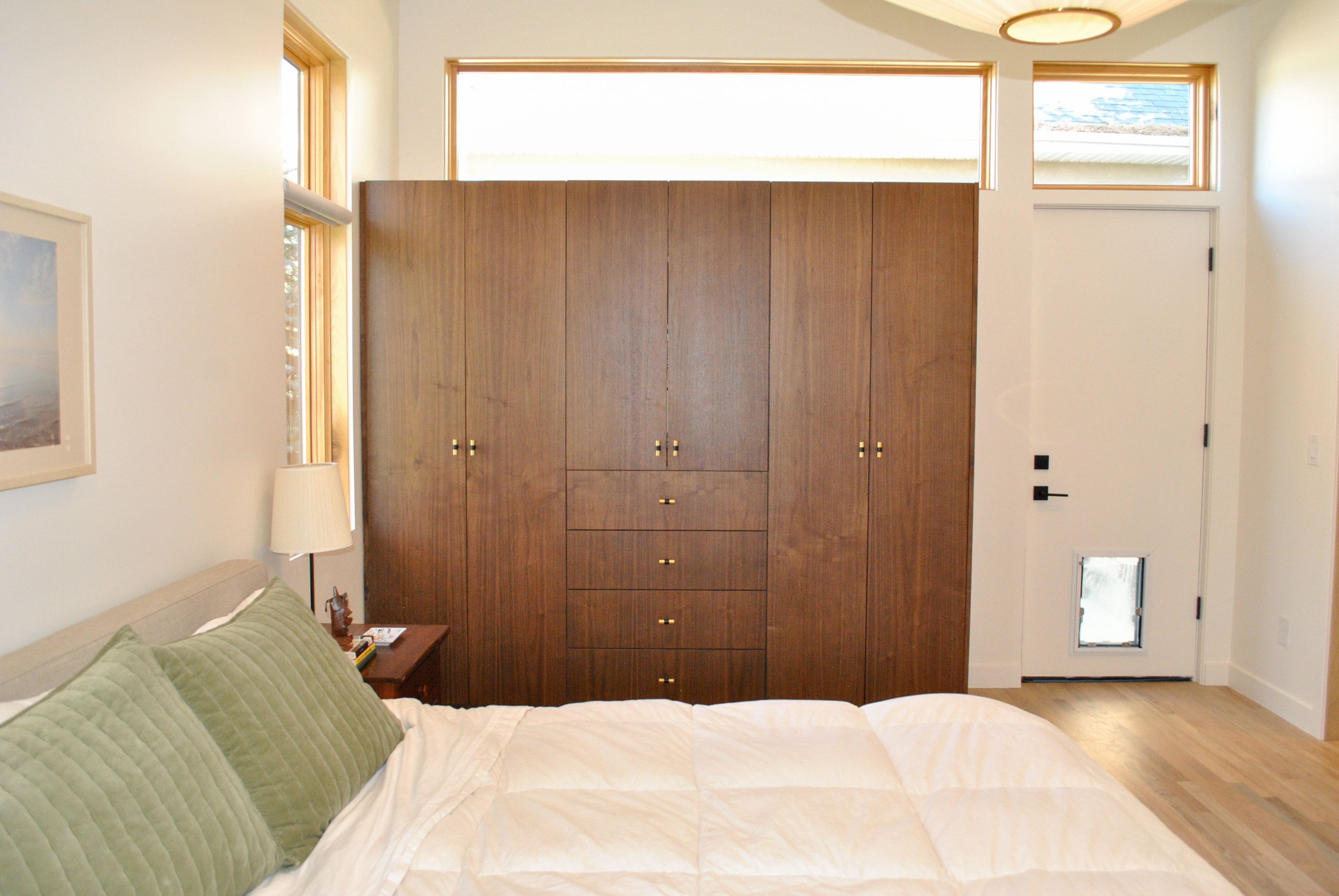 Primary bedroom with built-ins for the closet and a door with a dog door to the side.
