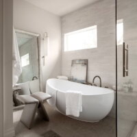 Thumbnail of http://Large%20freestanding%20tub%20in%20the%20primary%20bathroom.%20Along%20the%20wall%20is%20a%20bench%20with%20various%20decorations%20including%20a%20painting.%20On%20the%20other%20wall%20is%20a%20large%20mirror%20with%20a%20stool%20in%20front.