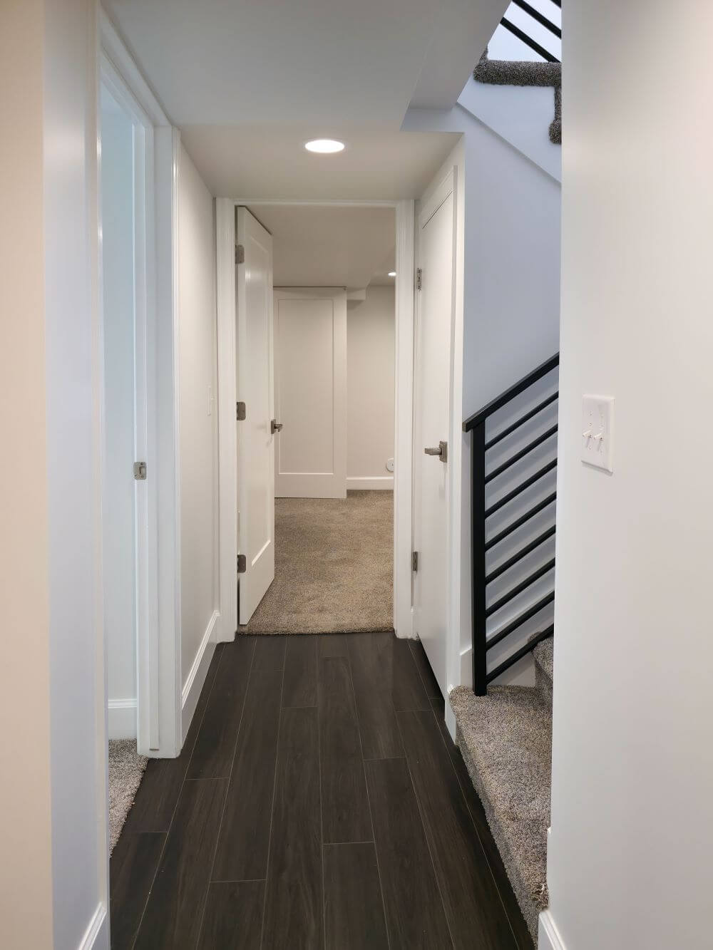 Finished basement apartment hallway with stairs and doors to the bedrooms.