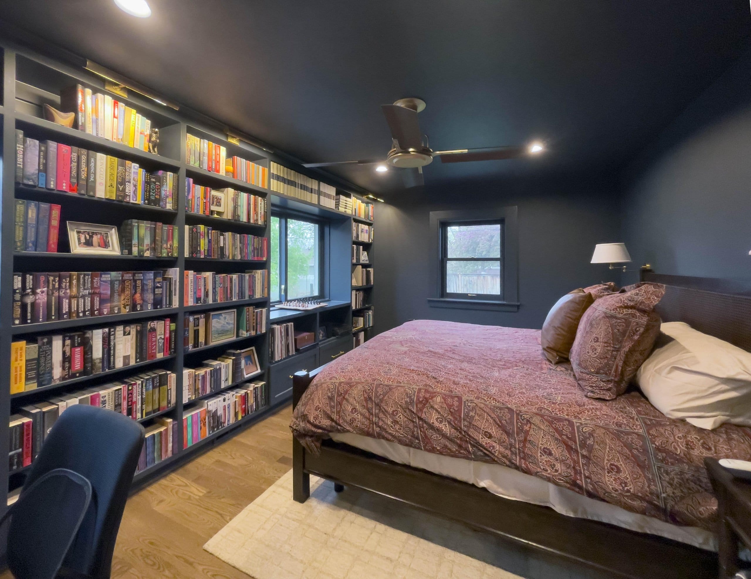 Primary bedroom with built-in bookshelves and a ceiling fan.