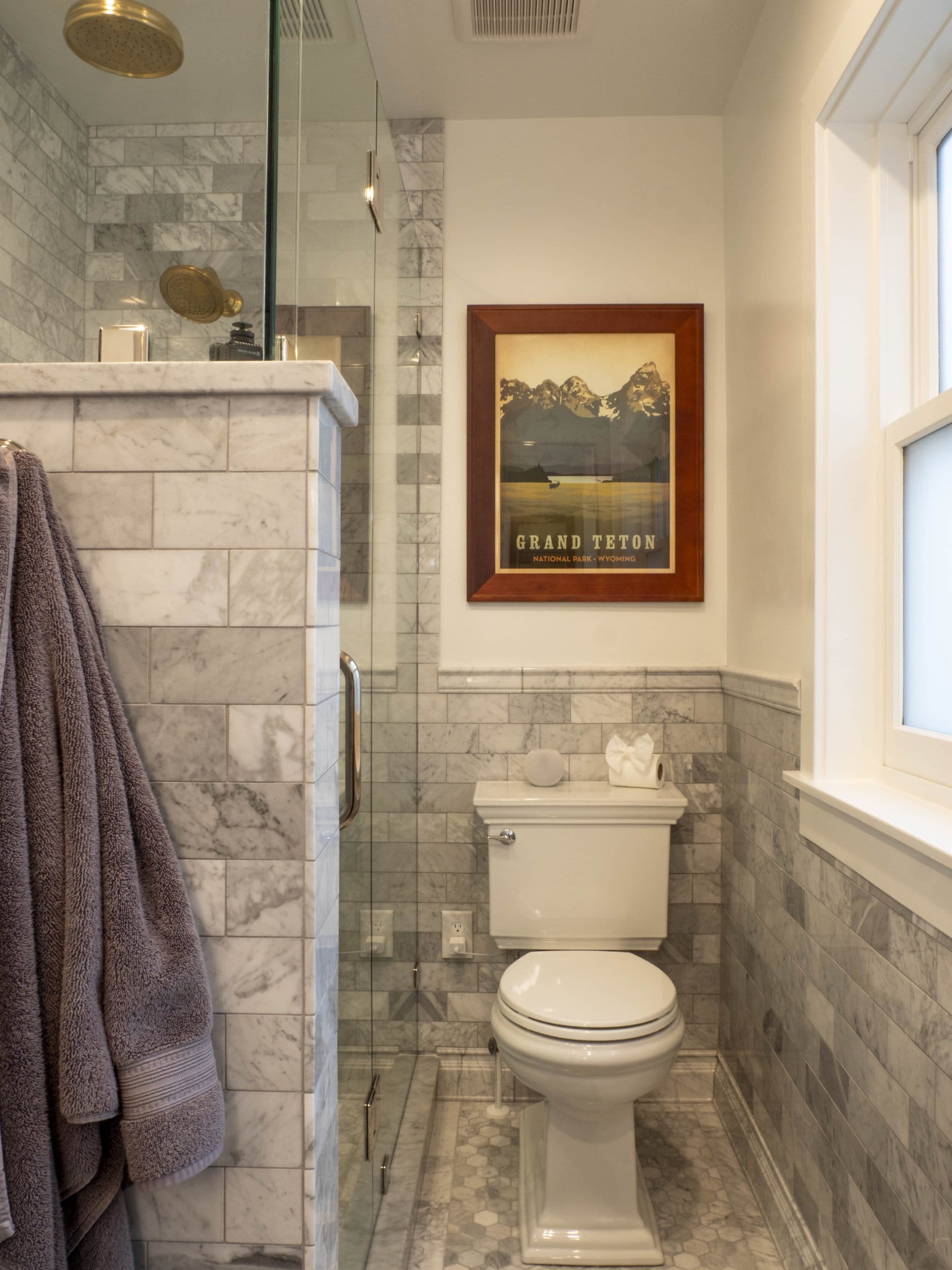 Primary bathroom toilet with a picture hung above and a large shower adjacent.