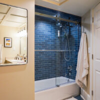 Thumbnail of http://Renovated%20tub%20and%20shower%20combination%20with%20blue%20tile%20in%20the%20basement%20bathroom.