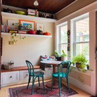 Thumbnail of http://A%20sitting%20area%20in%20a%20small%20addition%20with%20a%20built-in%20bench,%20round%20table,%20and%20two%20chairs.%20The%20space%20also%20includes%20shelves%20on%20the%20wall%20and%20lots%20of%20natural%20light%20from%20the%20windows.
