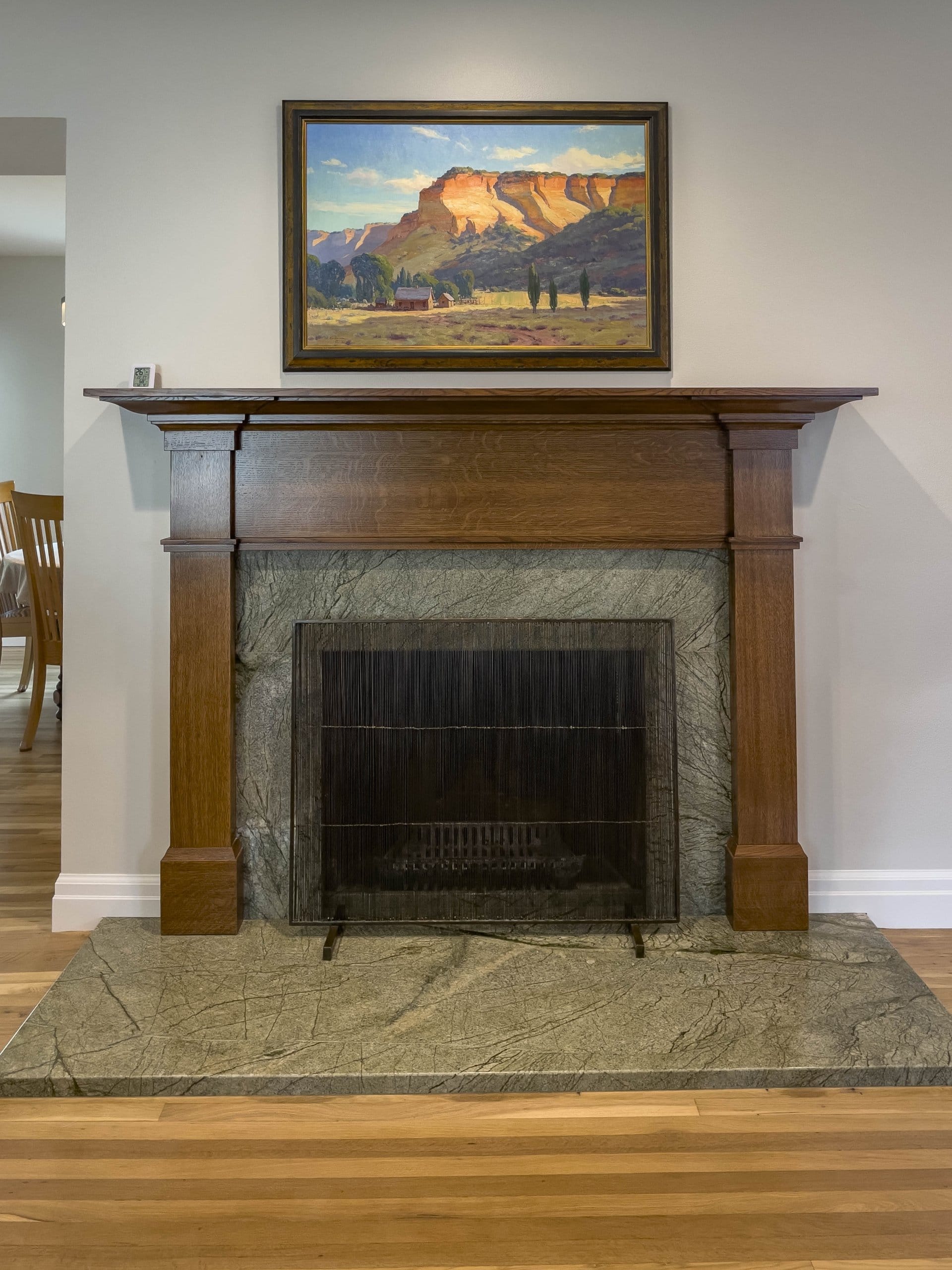 Living room fireplace with wood mantel and picture above.