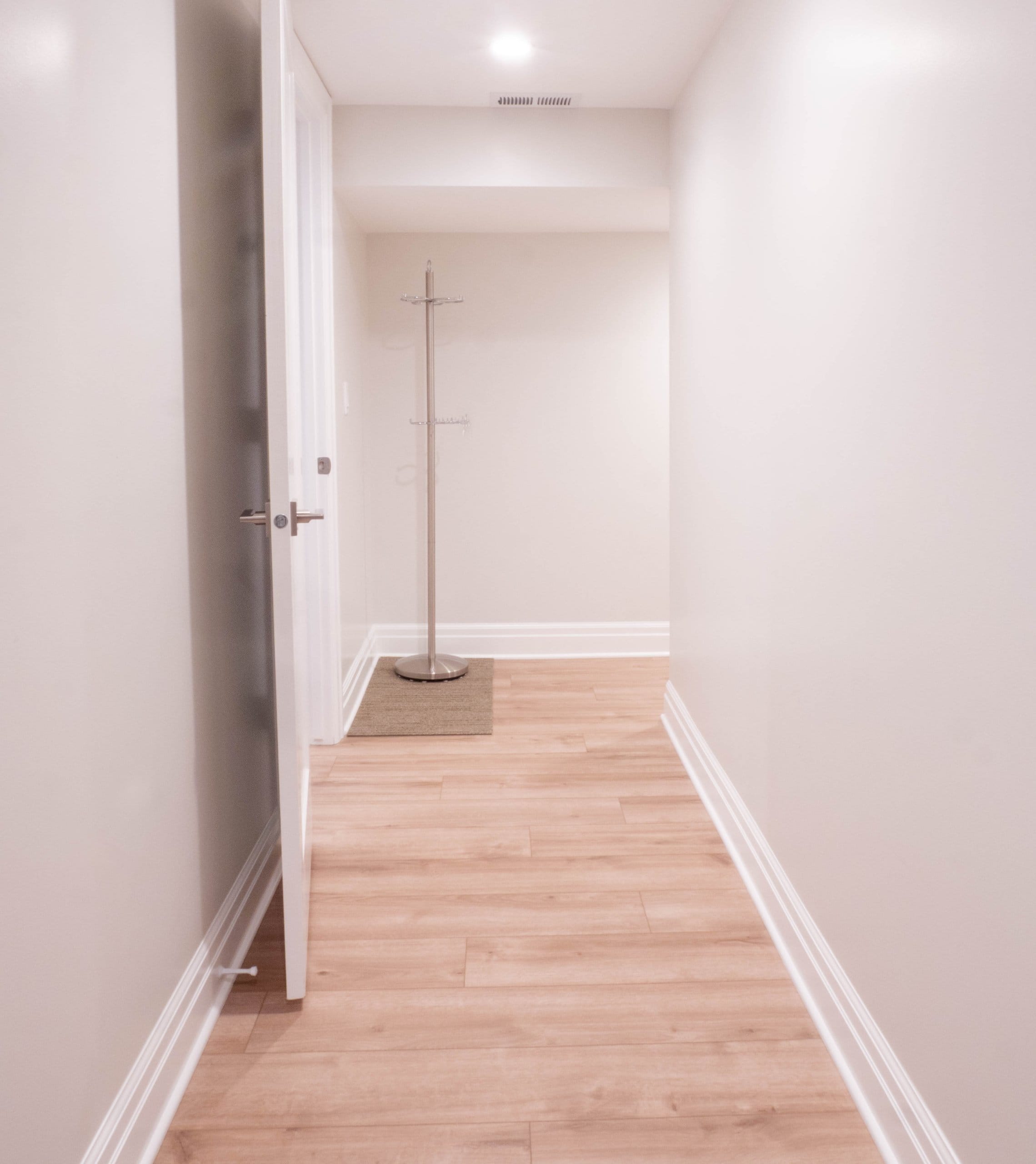 Hallway with coat rack and an open door.