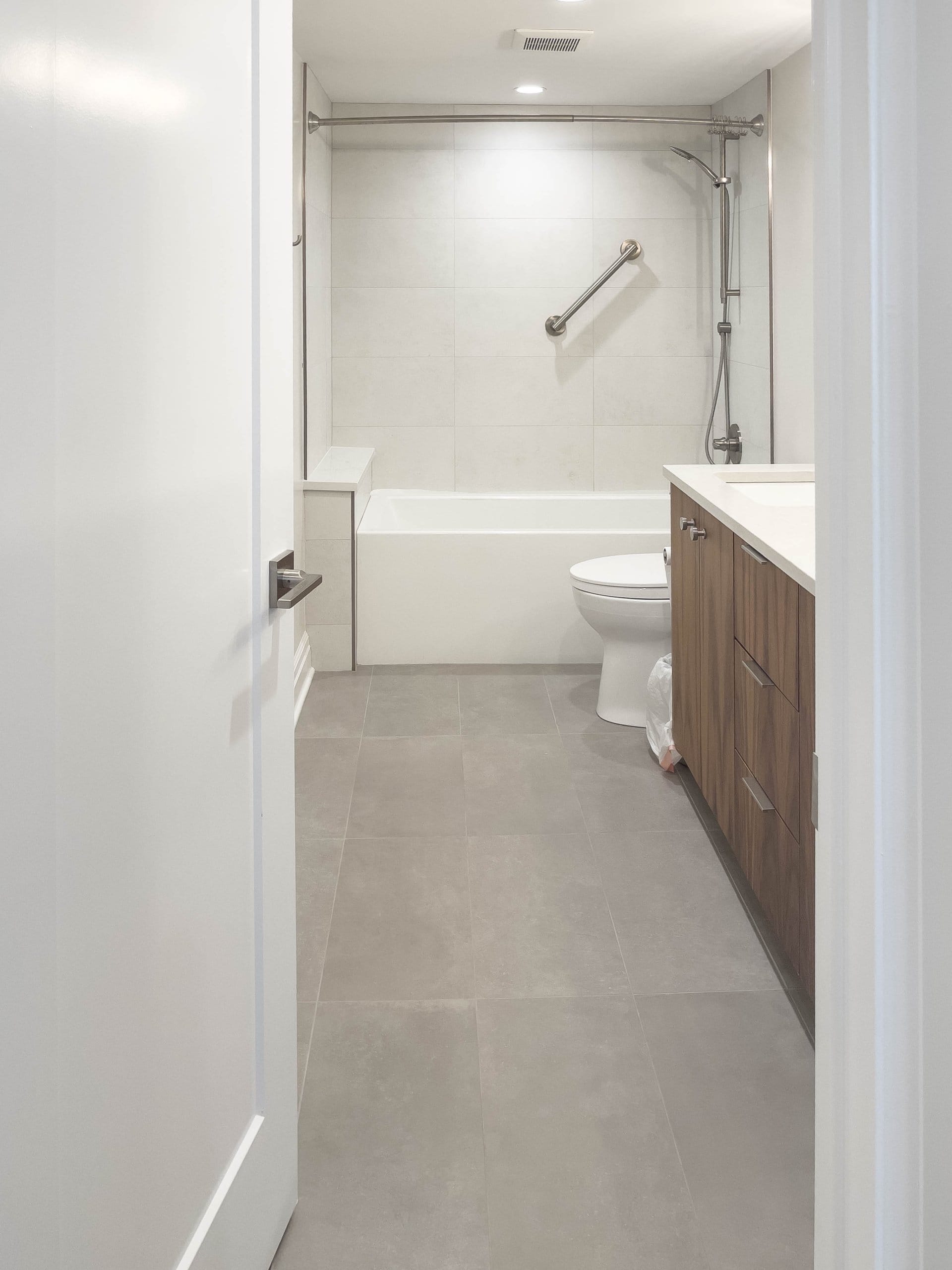 Bathroom looking past the sinks and toilet to the shower and tub combination.