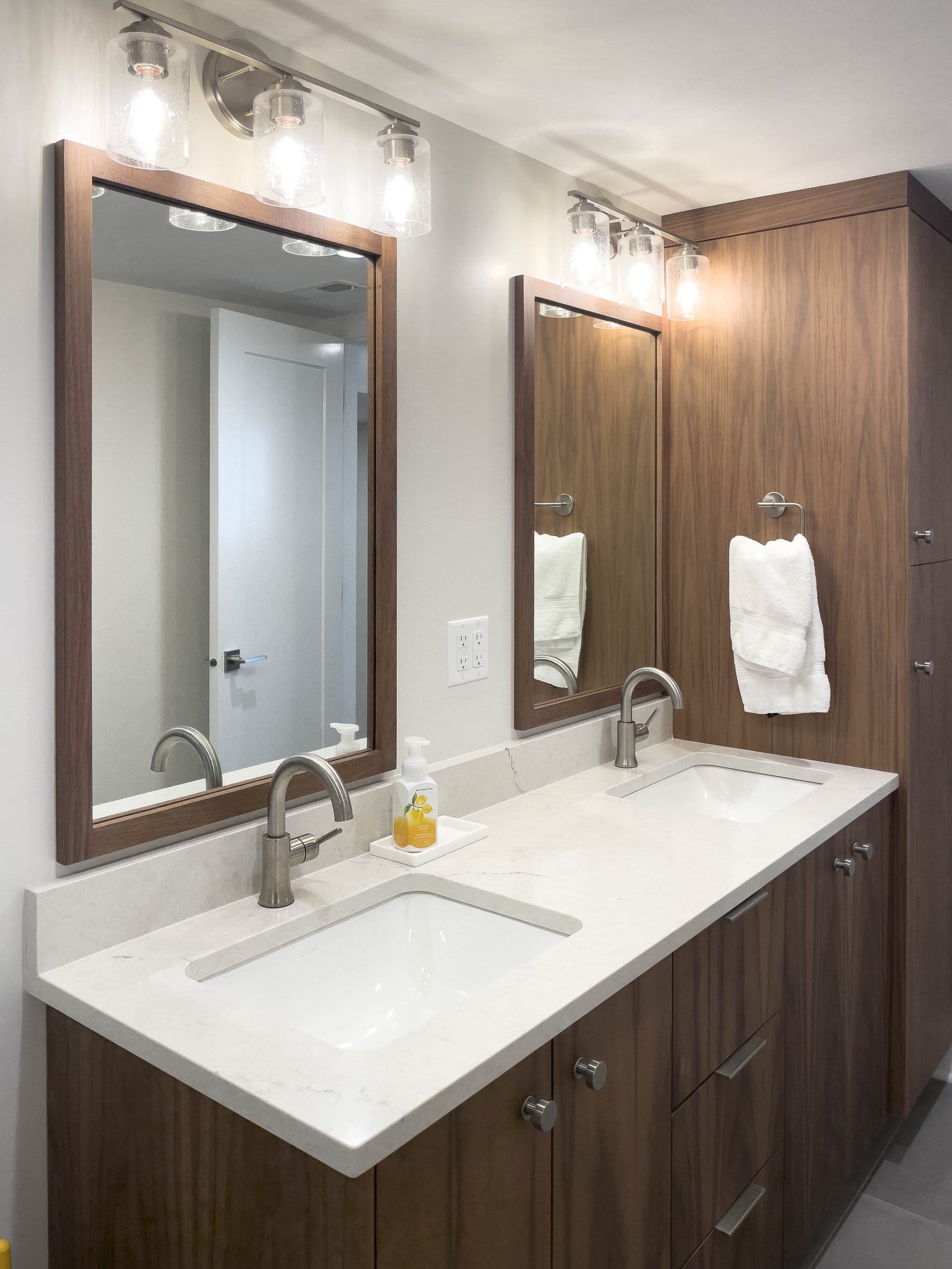Two sinks in a bathroom with mirrors and lights above.