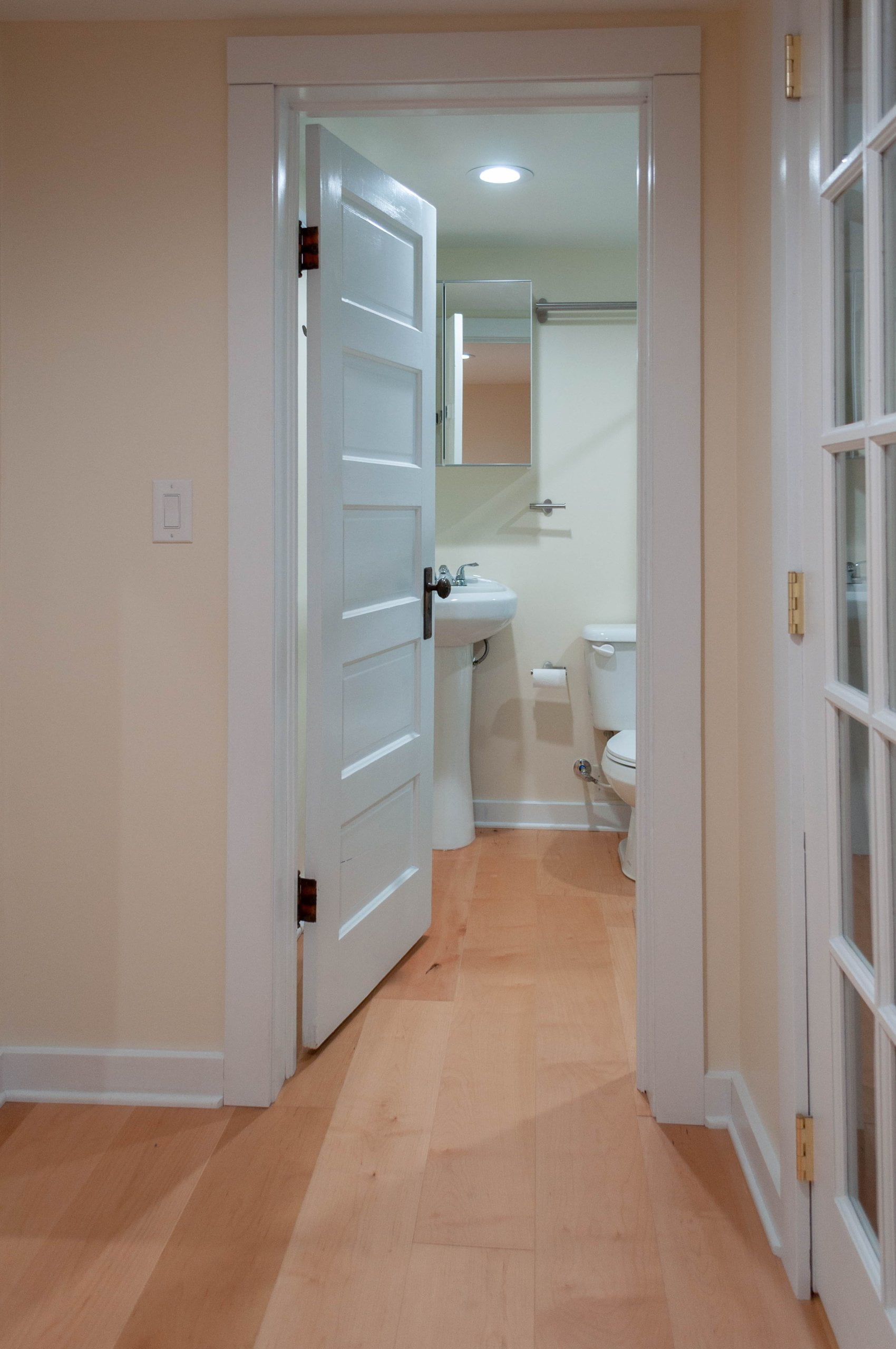 Looking from the hallway to the bathroom where a toilet and sink are.