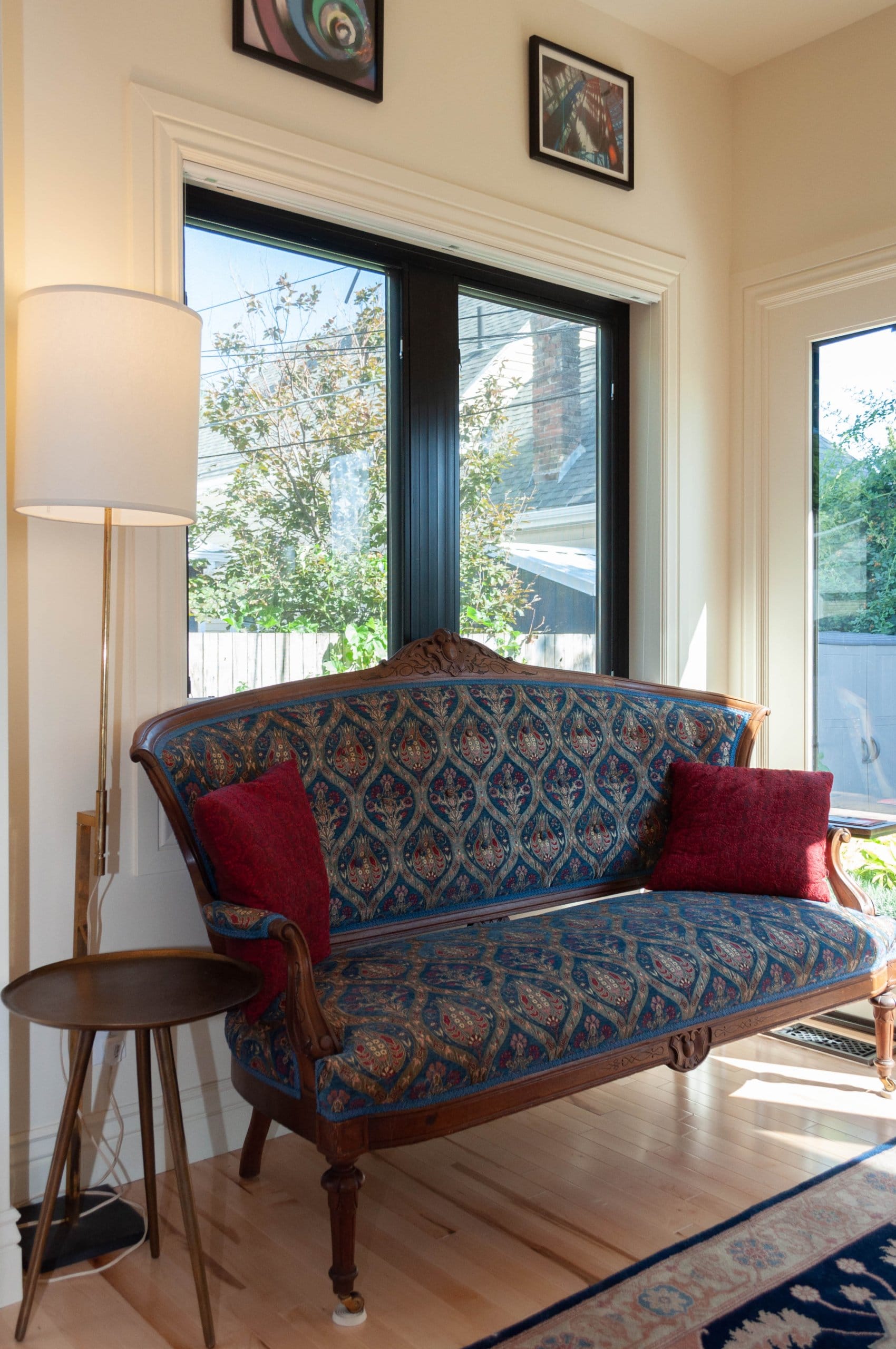 Couch placed under a window with a lamp and side table next to it.